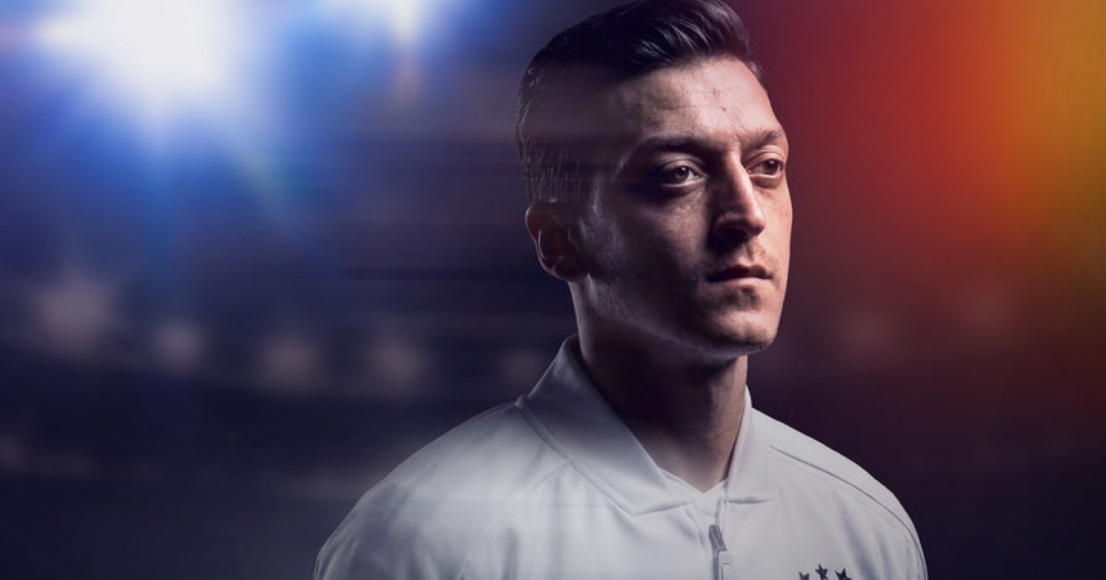 Mesut Özil blickt nachdenklich, im Hintergrund ist ein Stadion zu sehen