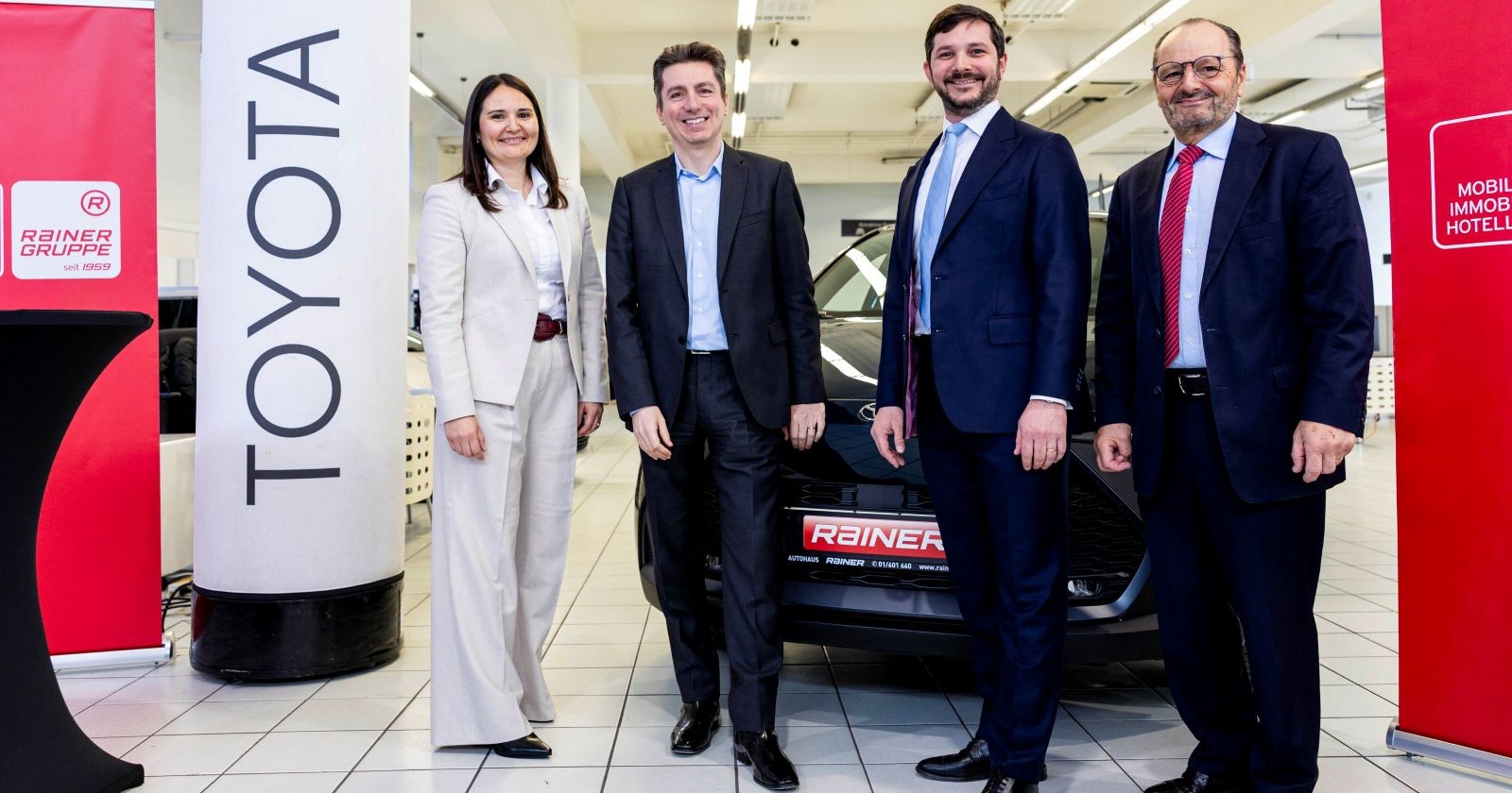 Eine Frau und drei Männer vor einem Pkw