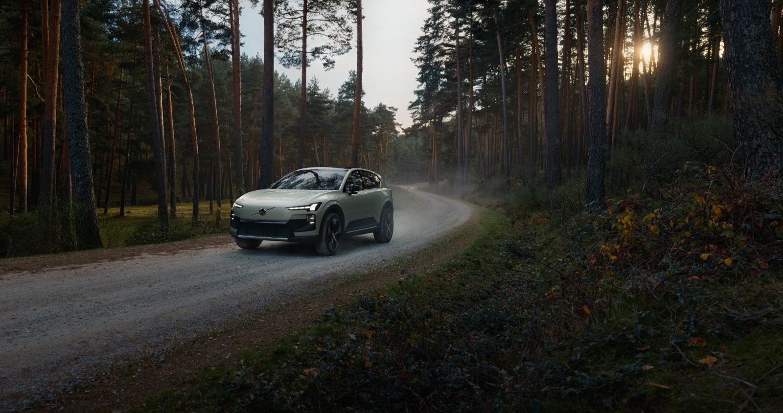 Der Volvo EX60 fährt auf einer Straße im Wald.