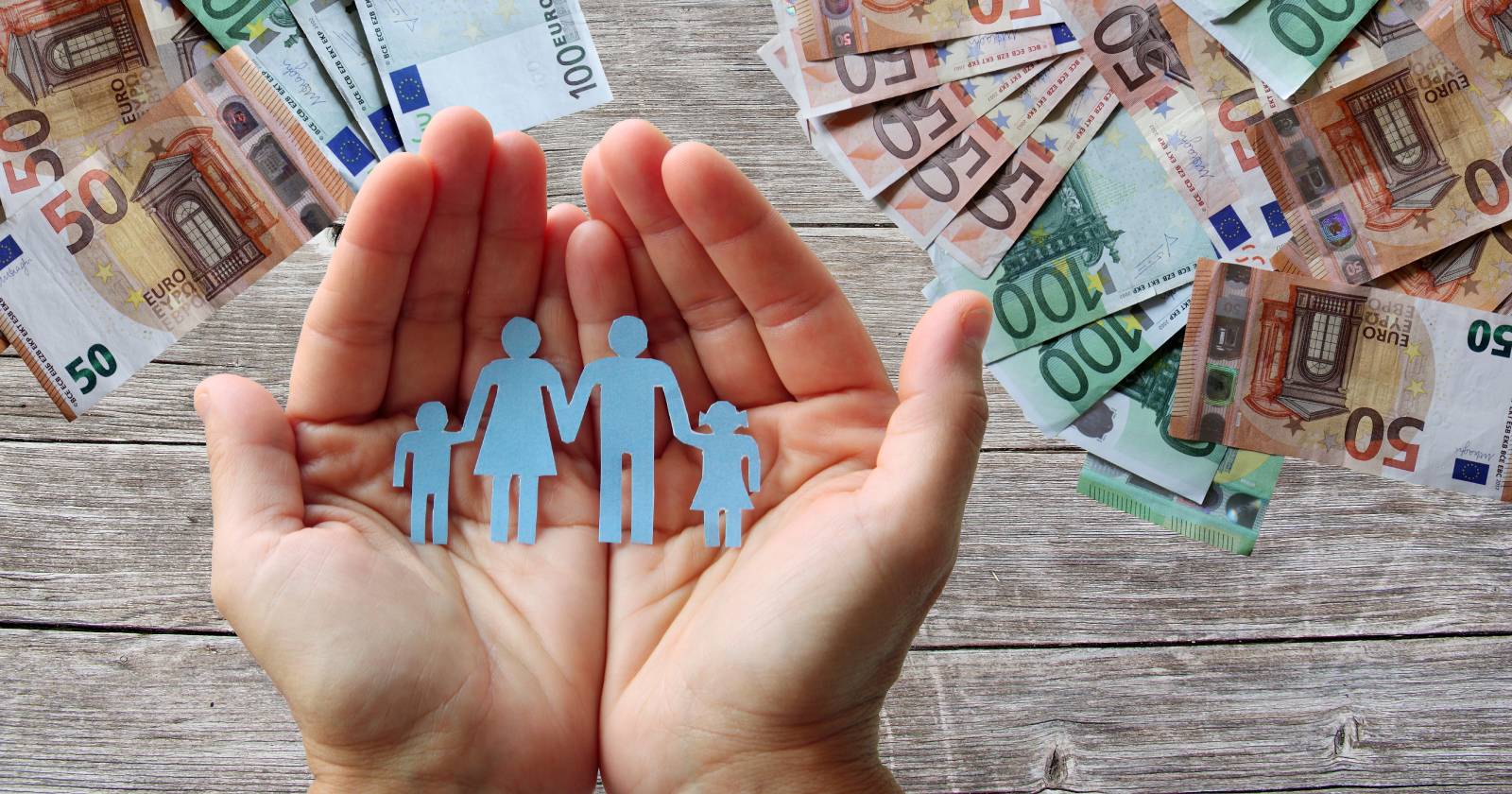 Offene Hände mit Papierausschnitt einer Familie über Euro-Banknoten | Credit: sal73it/Shutterstock