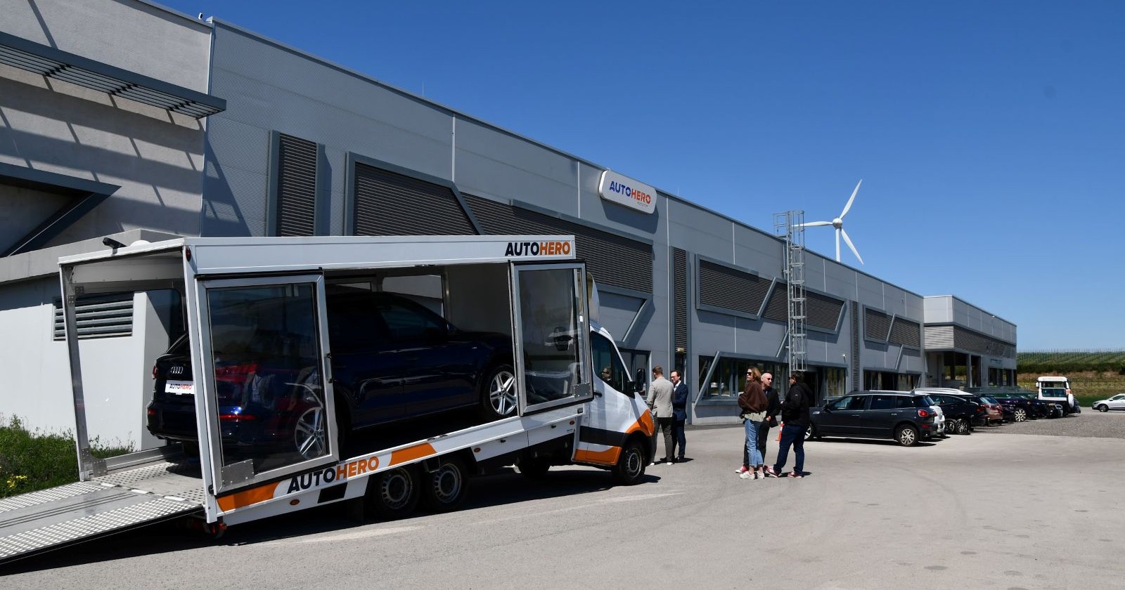 Pkw in einem Autotransporter vor einem Gewerbegebäude