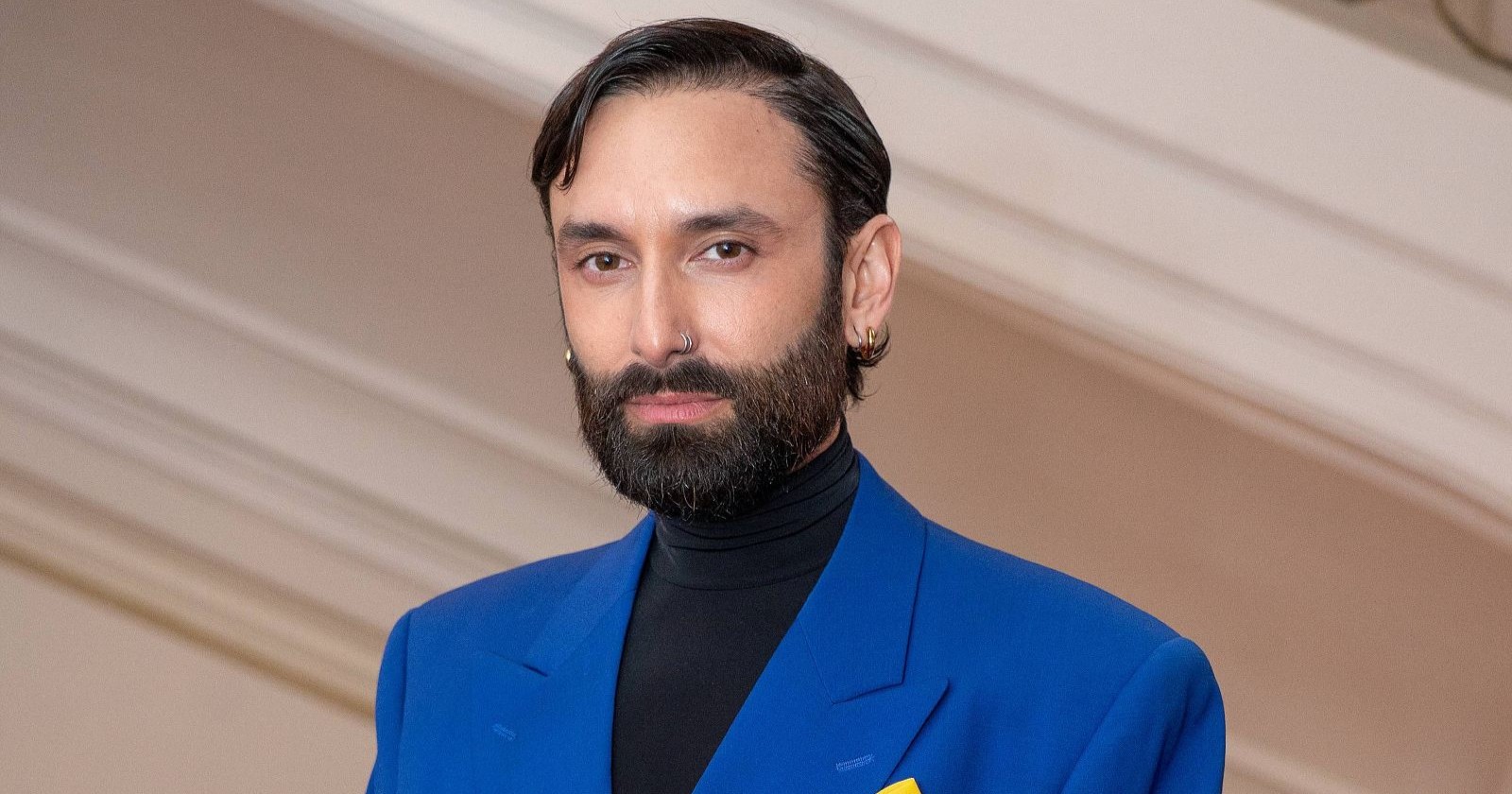 Conchita Wurst (Tom Neuwirth) im blauen Anzug bei einem Auftritt – übernimmt Rolle in „Die Fledermaus“ an der Volksoper Wien