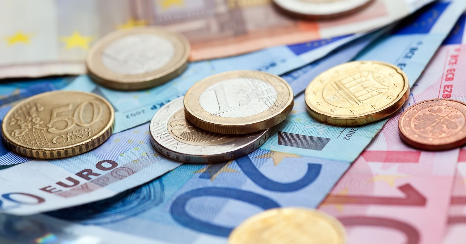 Geldmünzen und Banknoten auf einem Tisch dargestellt.