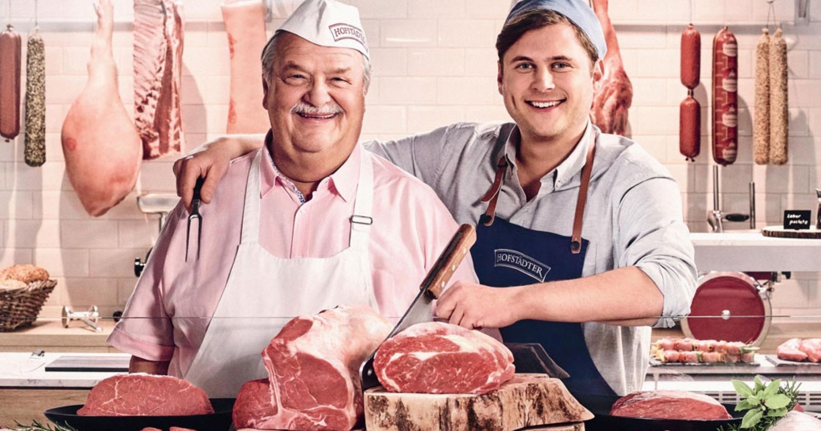 Hofstädter Senior und Junior in Metzgerei mit Fleisch und Würsten bei Schürzenübergabe Generationswechsel Billa Werbung