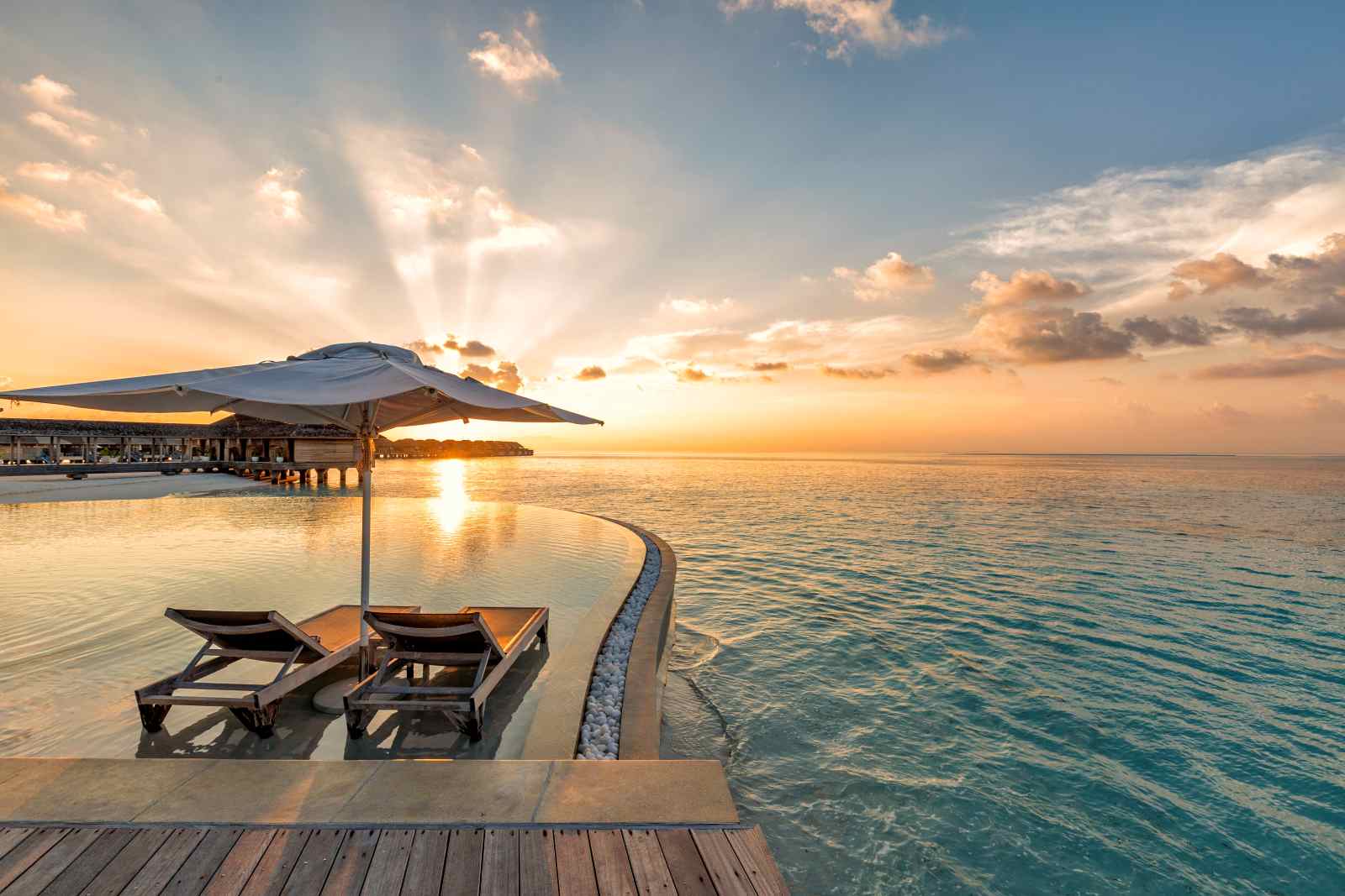 Liegestühle am Pool mit Blick auf das Meer bei Sonnenuntergang auf den Malediven
