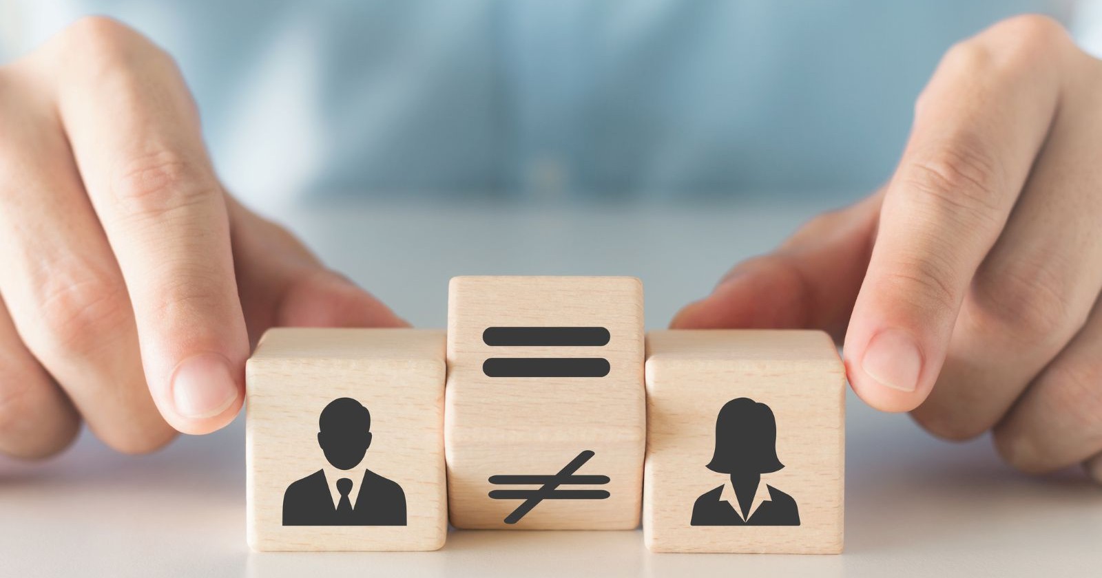 Drei Holzwürfel mit Symbolen Mann und Frau sowie ein Ungleichzeichen