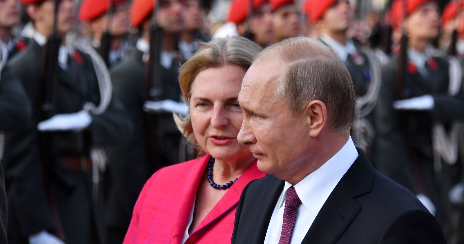 Karin Kneissl neben Wladimir Putin bei einem offiziellen Termin mit Militär im Hintergrund