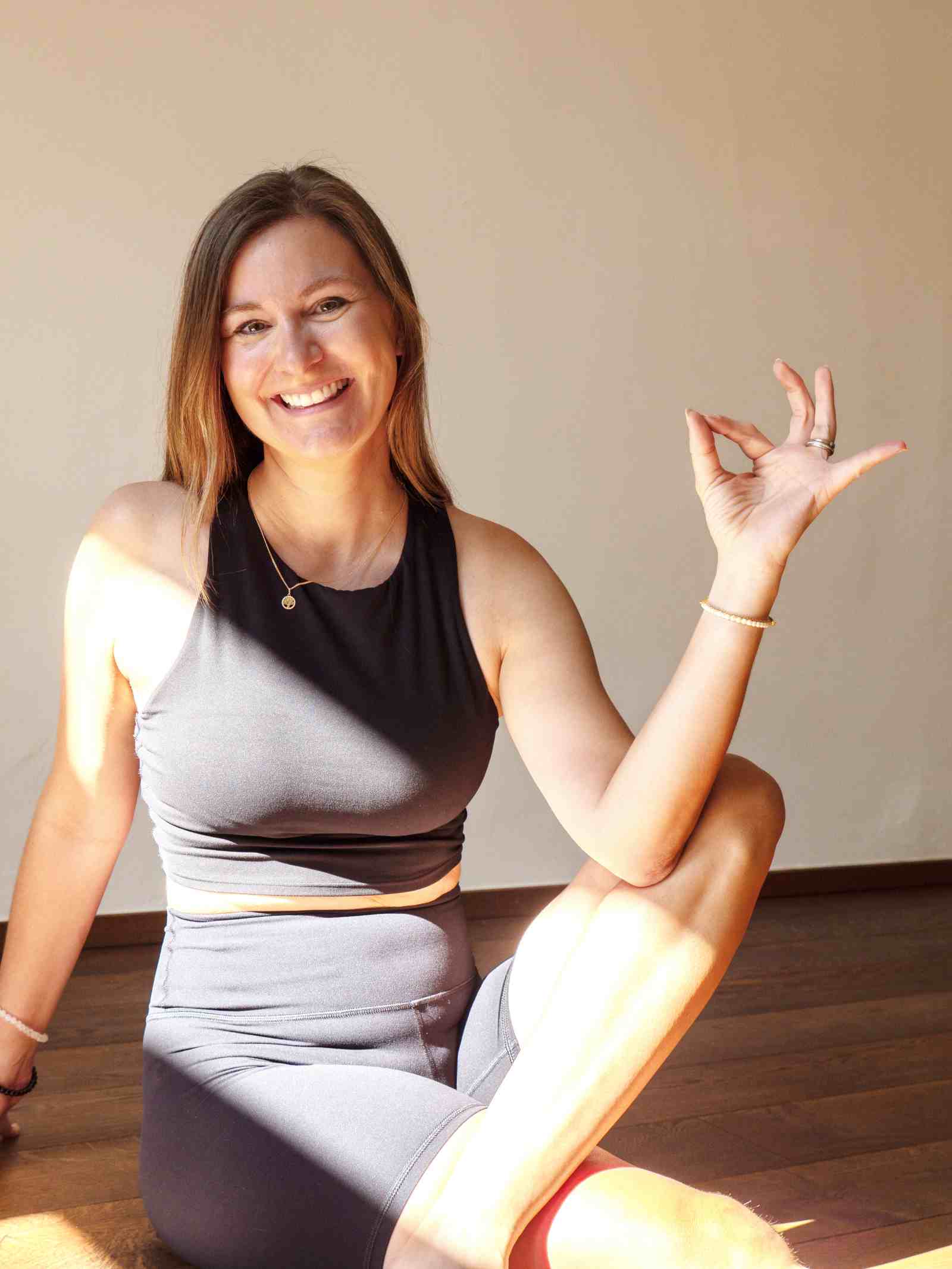 Katharina Tschurtschenthaler sitzt in Yoga-Kleidung auf dem Boden und lächelt