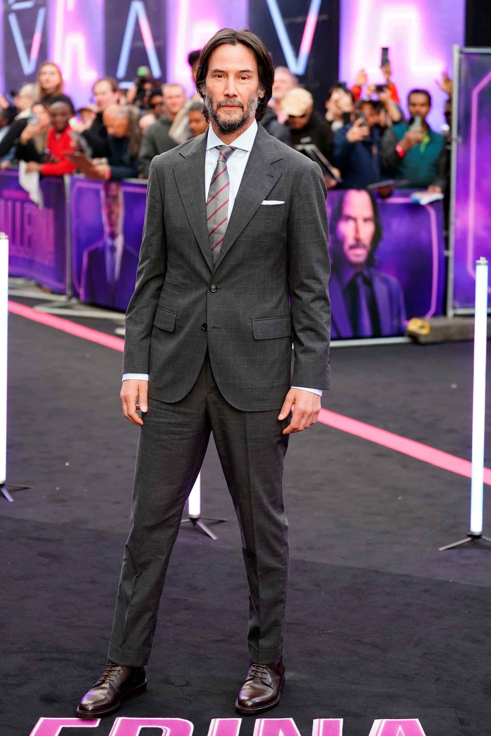 Schauspieler Keanu Reeves im grauen Anzug bei einer Filmpremiere auf dem roten Teppich.