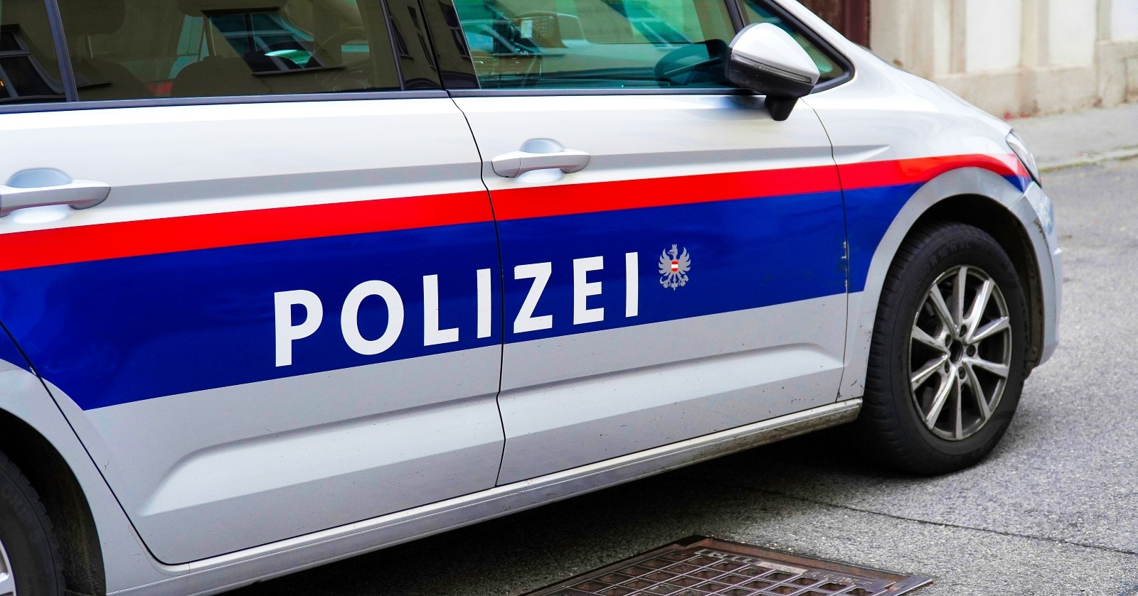 Ein Polizeiauto in Österreich Wien ist in einer ruhigen Straße in einer europäischen Stadt in der Nähe eines Abflusses abgestellt.