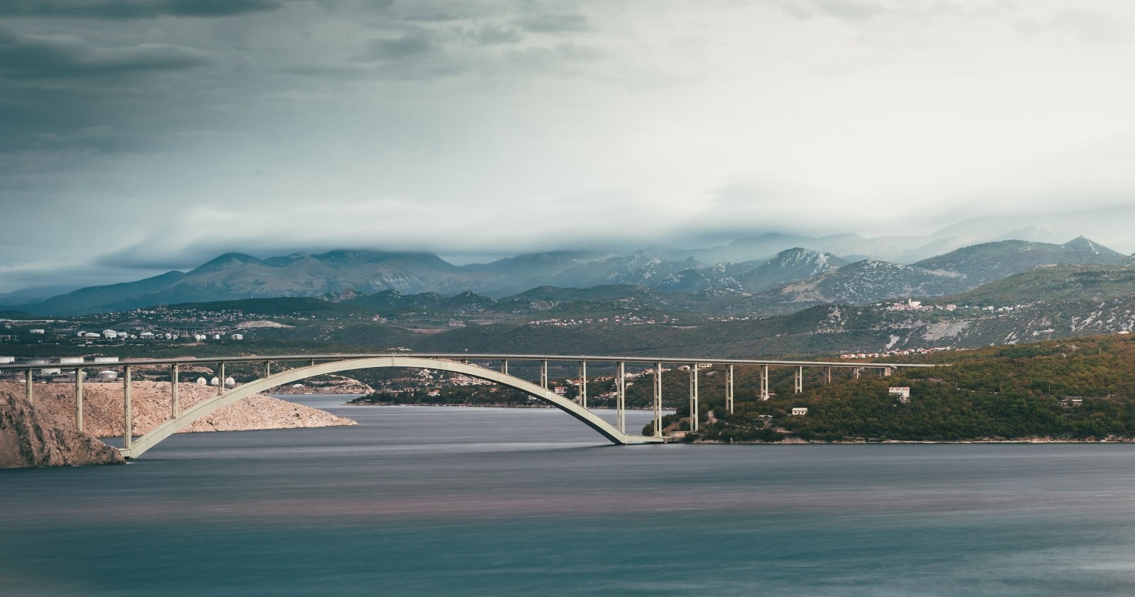 Krk-Brücke gesperrt: Krk Bogenbrücke in Kroatien über die Adria gegen die vom Nebel bedeckten Berge erobert.