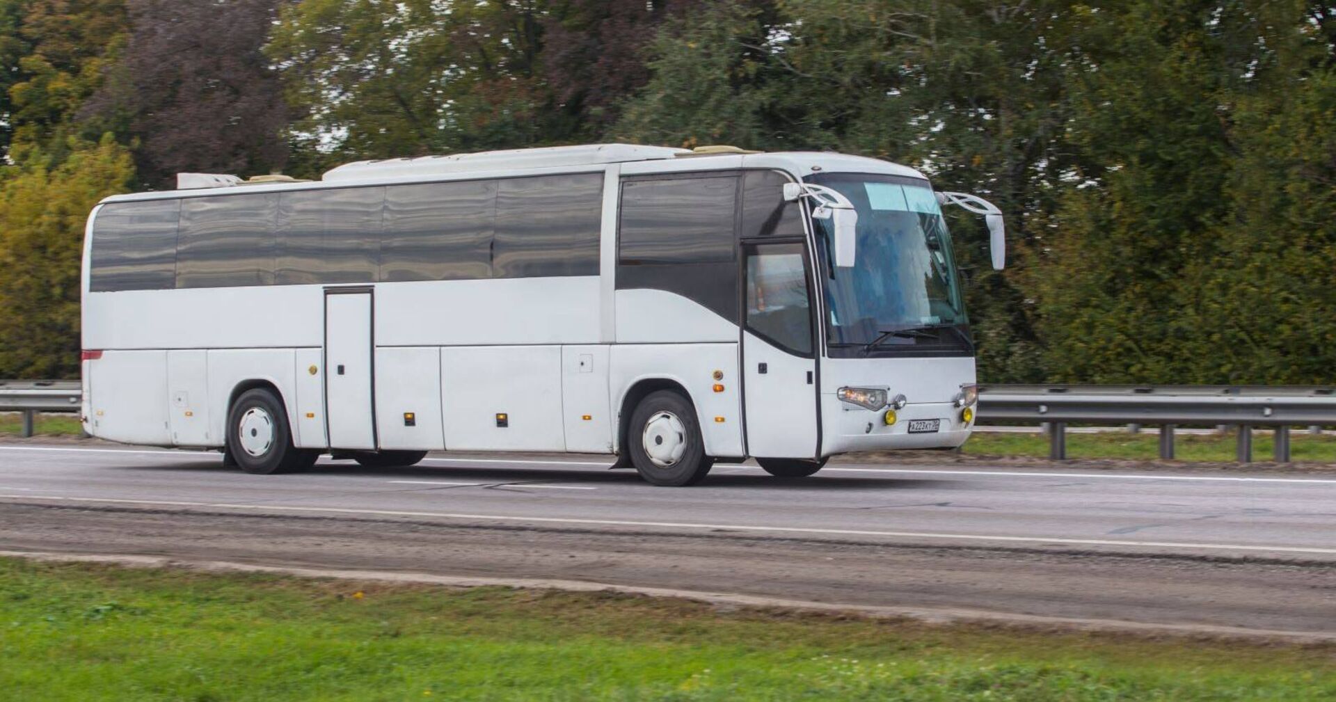 Ein weißer Reisebus fährt auf einer Landstraße.