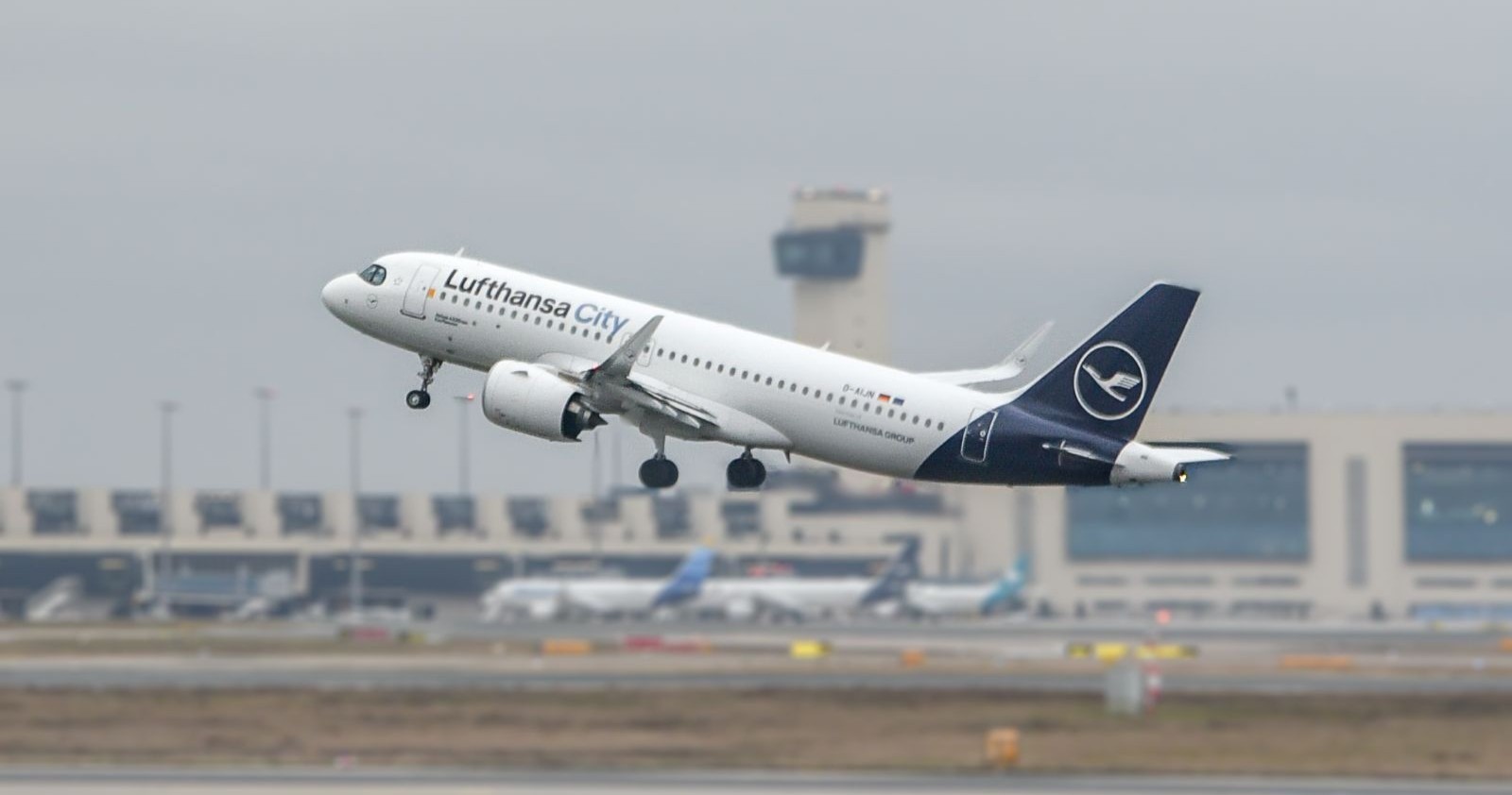 Eine Lufthansa-Maschine hebt von einem Flughafen ab.