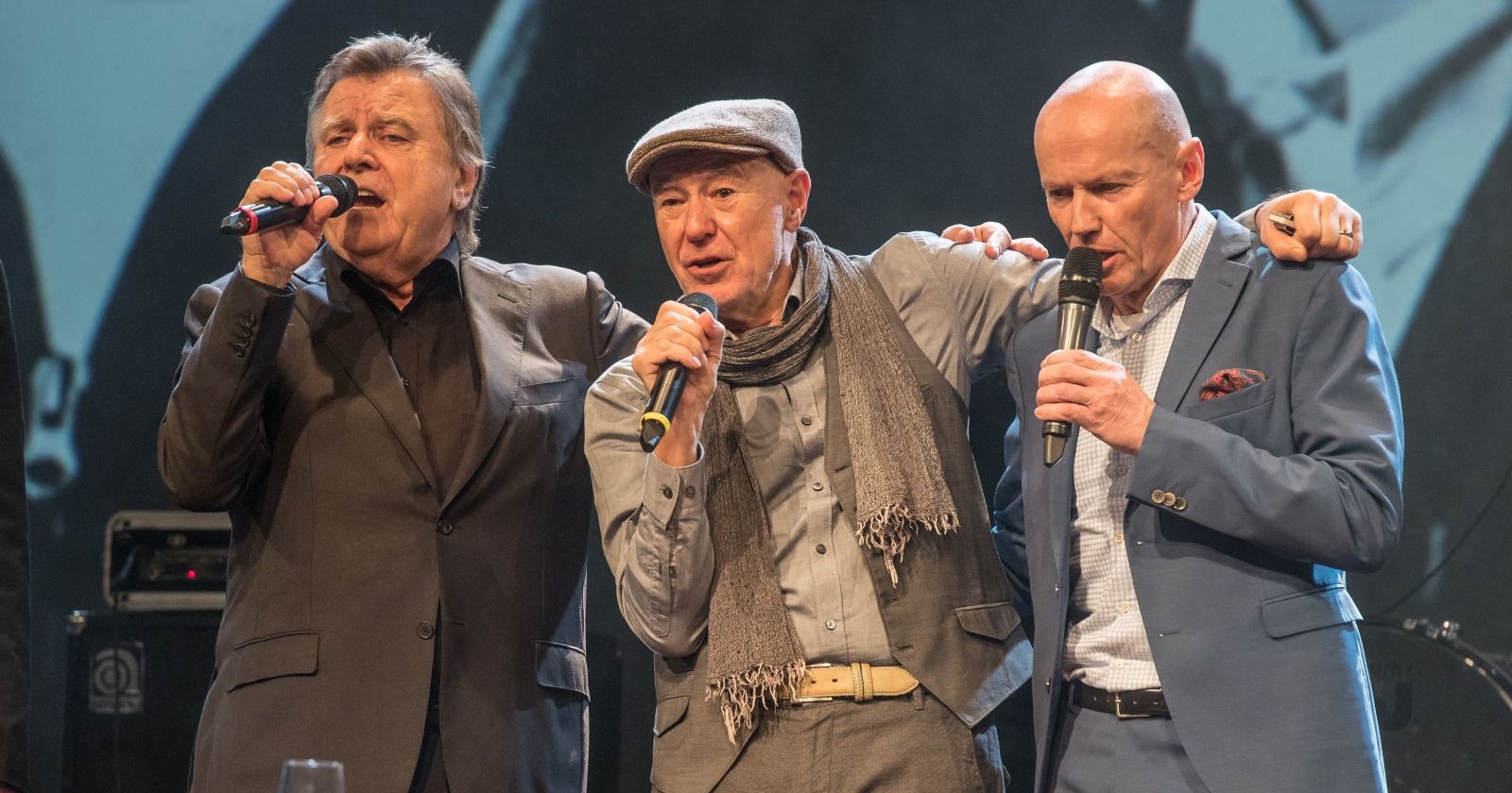 Peter Resetarits gemeinsam mit Willi Resetarits auf der Bühne bei einem emotionalen Konzertauftritt mit Mikrofonen
