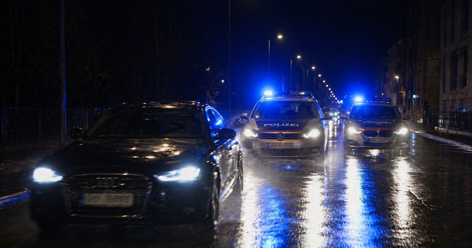 Polizeiautos verfolgen nachts einen schwarzen Audi bei nasser Fahrbahn in Wien-Döbling während einer Raser-Verfolgungsjagd.