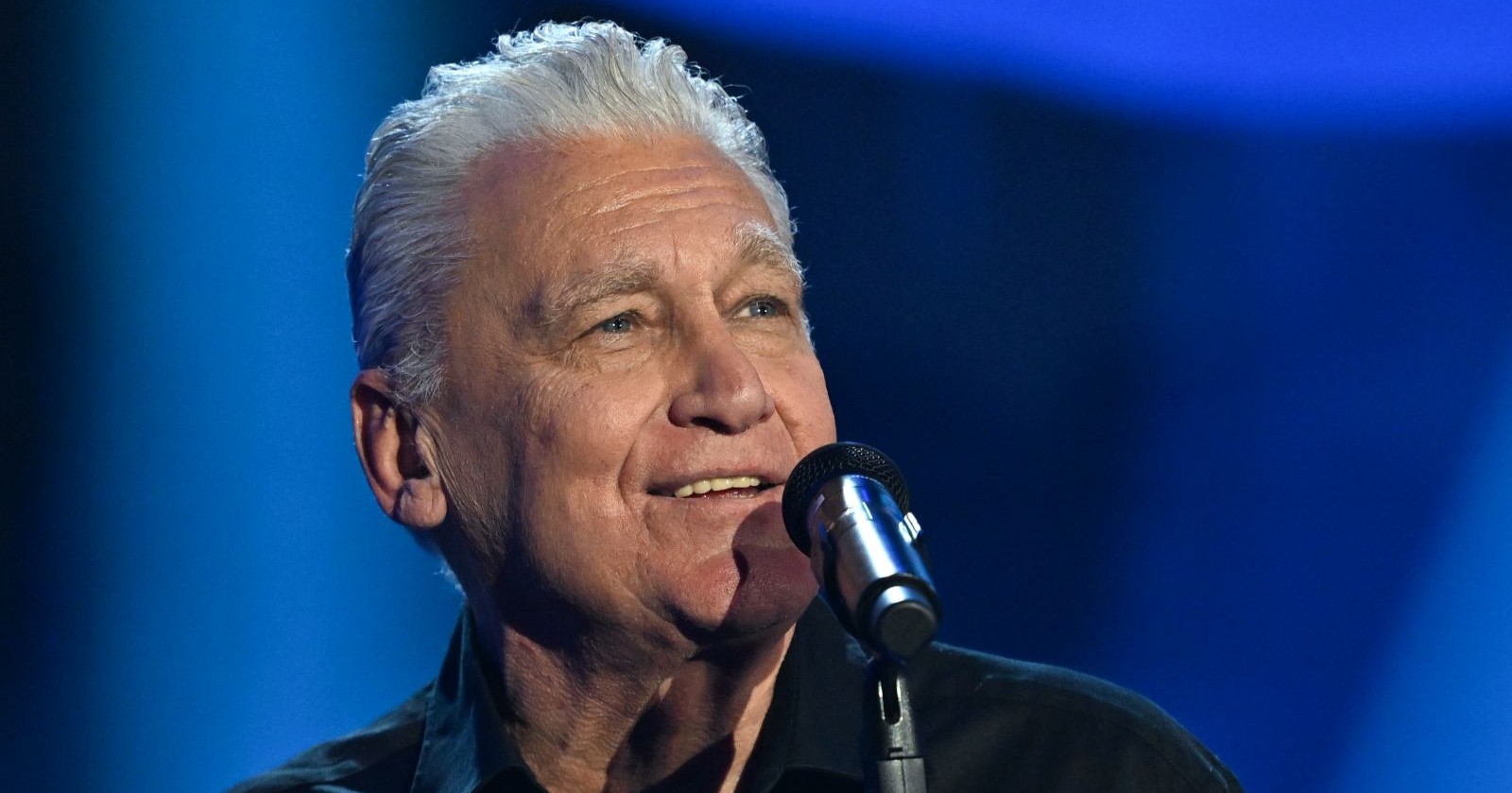 Rainhard Fendrich live auf der Bühne mit Mikrofon während seiner Jubiläumstour zum Album „45 Jahre“