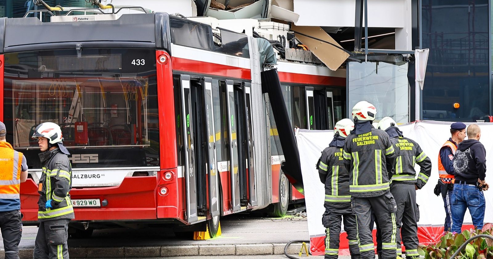 Einsatzkräfte am Unfallort in Salzburg-Itzling, wo ein Obus in die Fassade eines Billa-Marktes gekracht ist