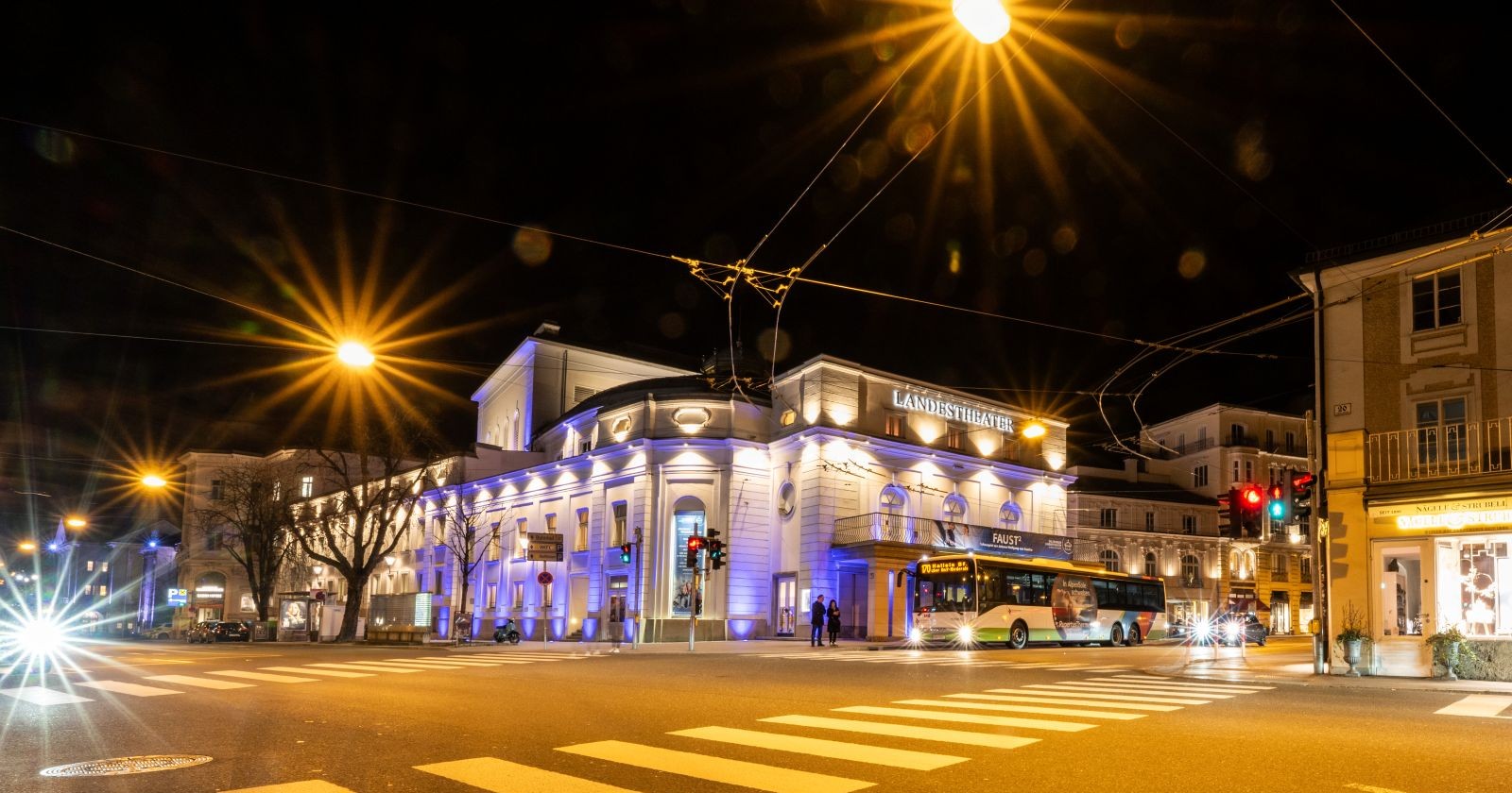 Salzburger Landestheater bei Nacht mit beleuchteter Fassade und Straßenverkehr in Salzburg