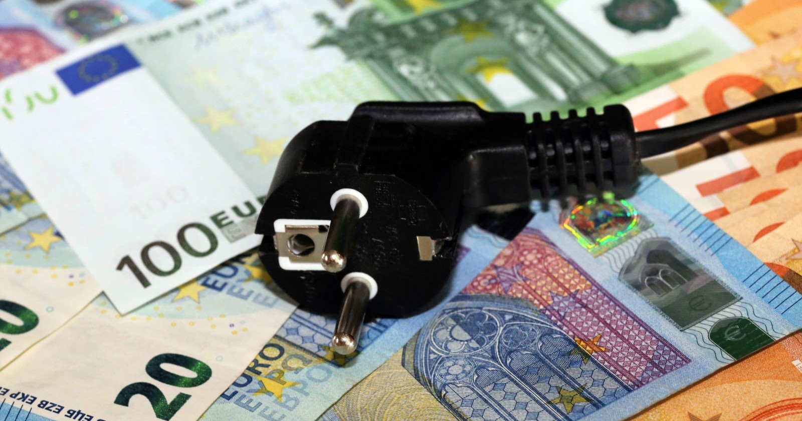 Stromstecker liegt auf Euro-Banknoten und symbolisiert steigende Energiekosten und Stromrechnung in Österreich