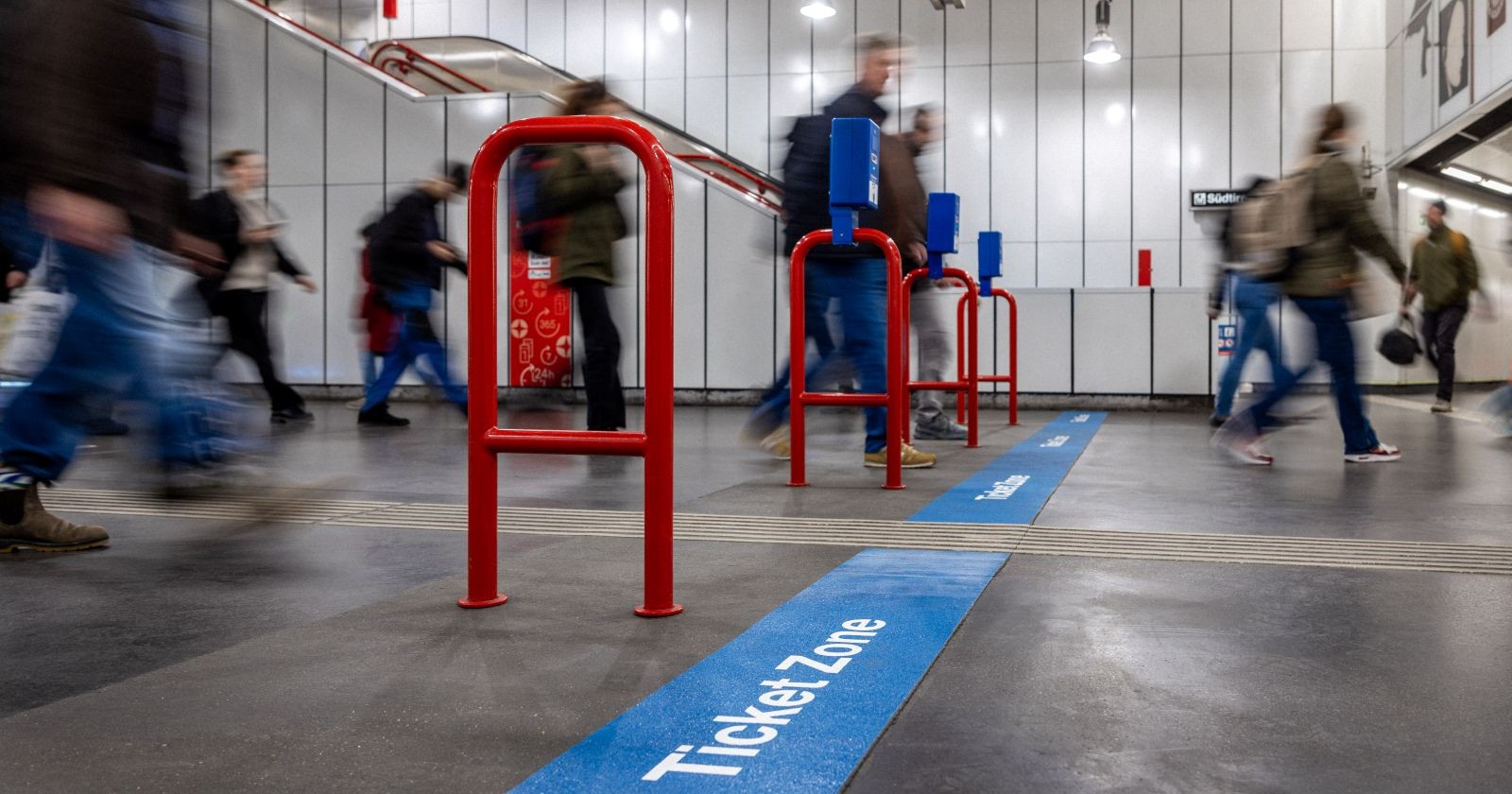 Passanten überqueren die neue blaue Bodenmarkierung am Wiener Hauptbahnhof