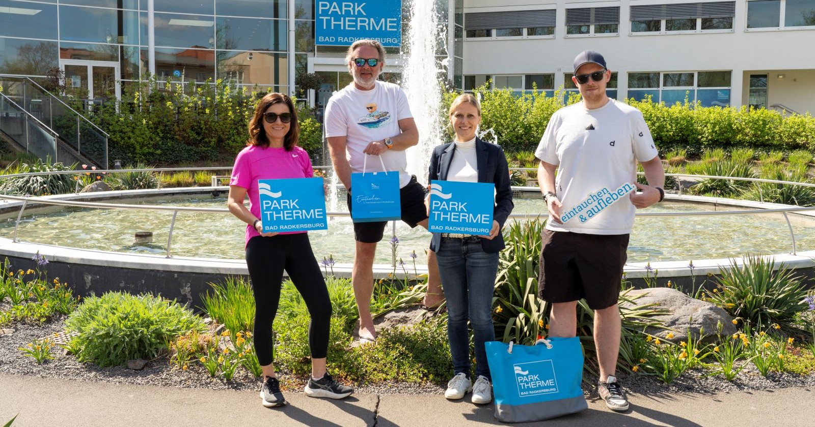 Vier Menschen posieren vor einem Springbrunnen