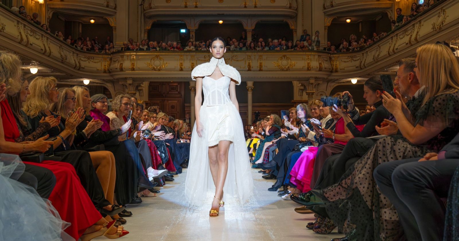 Model geht in einem weißen Kleid über den Laufsteg