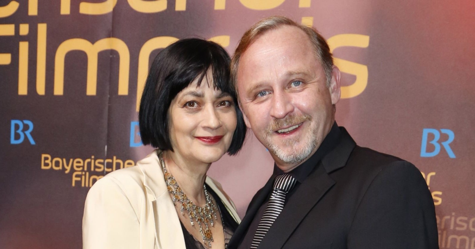 Alexander Held mit Ehefrau Patricia bei Filmpremiere, beide lächelnd nebeneinander, vor Event-Hintergrund