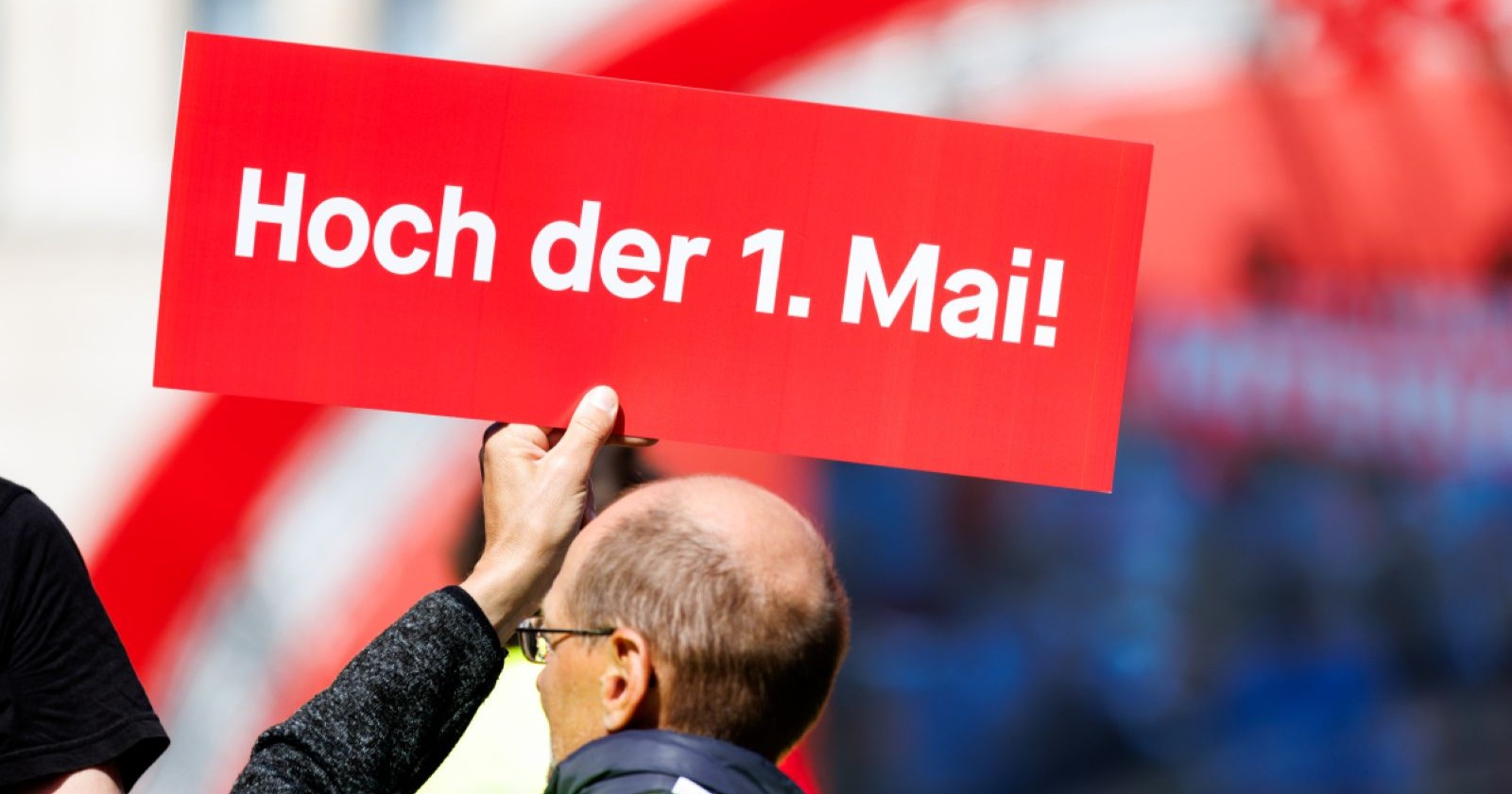 Teilnehmer einer 1.-Mai-Demonstration halten ein rotes Schild mit der Aufschrift „Hoch der 1. Mai!“ bei einer politischen Kundgebung in Österreich