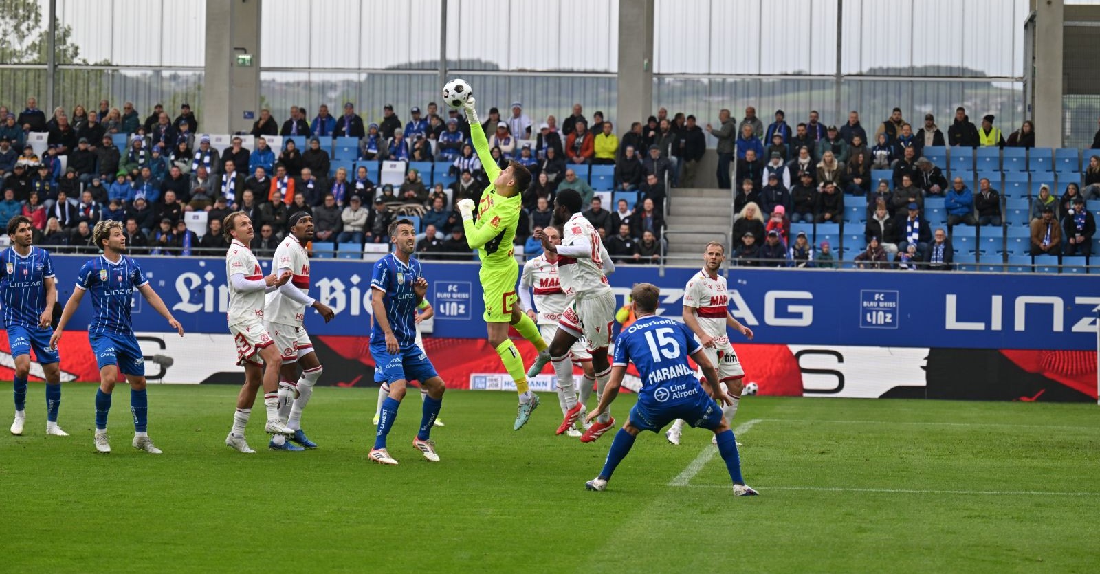 Torhüter faustet Ball im Strafraum bei Blau-Weiß Linz gegen GAK, mehrere Spieler im Zweikampf während Abstiegskampf in der Bundesliga
