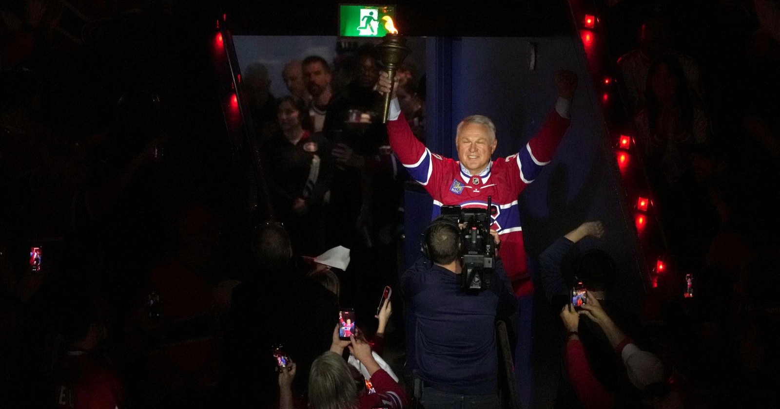 Der ehemalige Eishockey-Profi Claude Lemieux hebt lächelnd die Hände auf dem Eis bei einer Ehrung