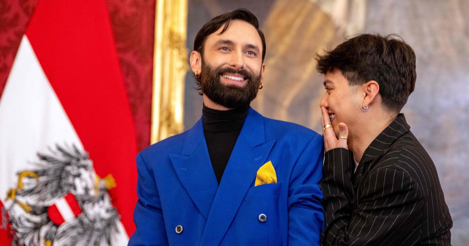 JJ und Conchita Wurst lachen gemeinsam bei einem Pressetermin in Wien. Die beiden bringen ihren erfolgreichen „Bussibaba“-Podcast erstmals live auf die Bühne des Vienna Pride Community Fest.