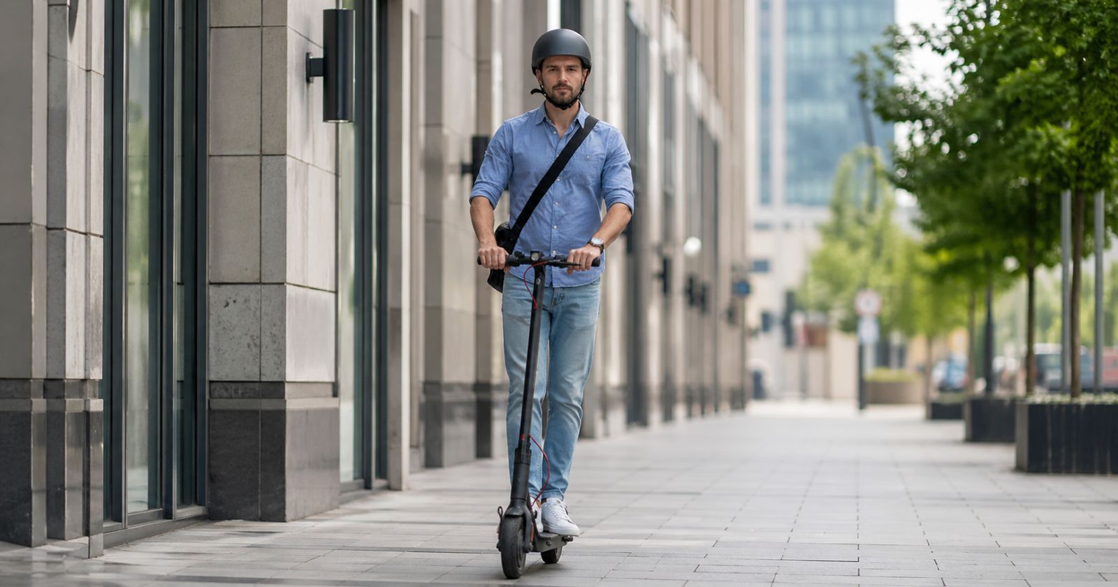 Mann fährt mit E-Scooter und trägt Helm auf Gehweg in der Stadt im Zusammenhang mit neuen StVO-Regeln für E-Scooter und E-Bikes, Helmpflicht nur für Kinder