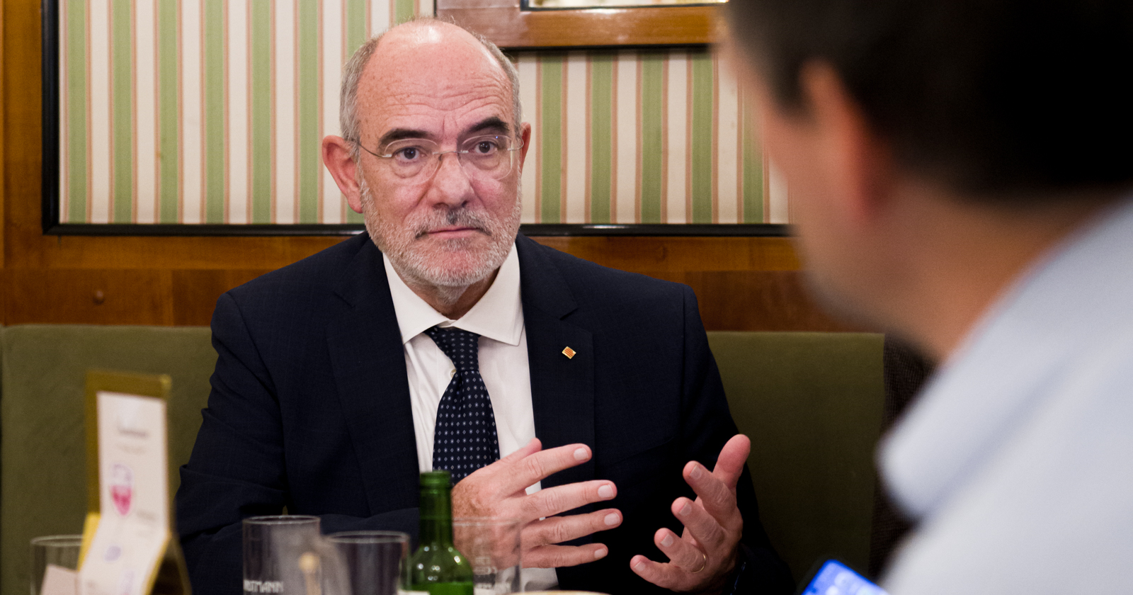 katalanische Minister für Europäische Union und Auswärtiges in Anzug und mit Brille beim Gespräch im Kaffeehaus