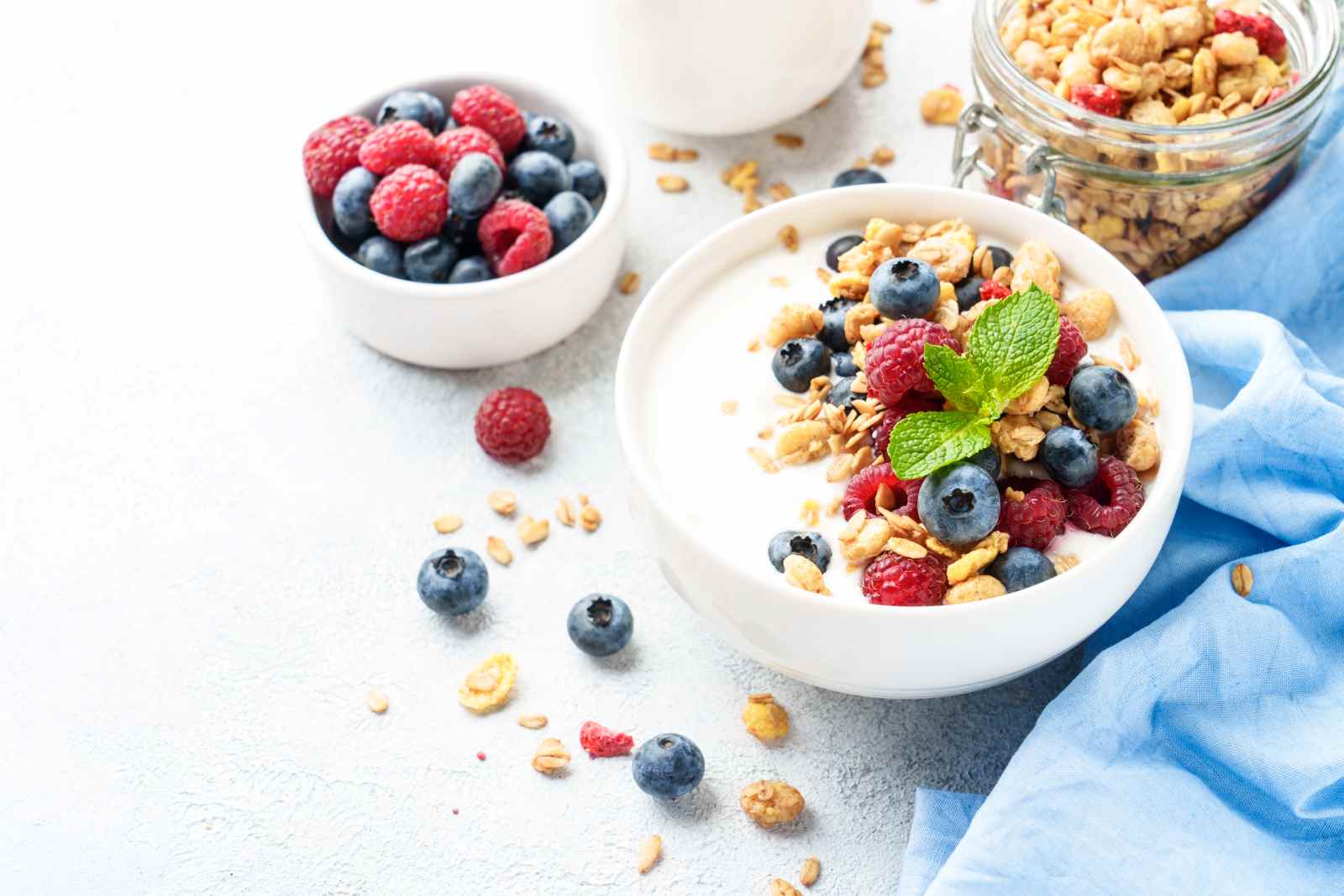 Schüssel mit Joghurt, Beeren und Granola auf hellem Tisch – leichte, eiweißreiche Ernährung für warme Sommertage.