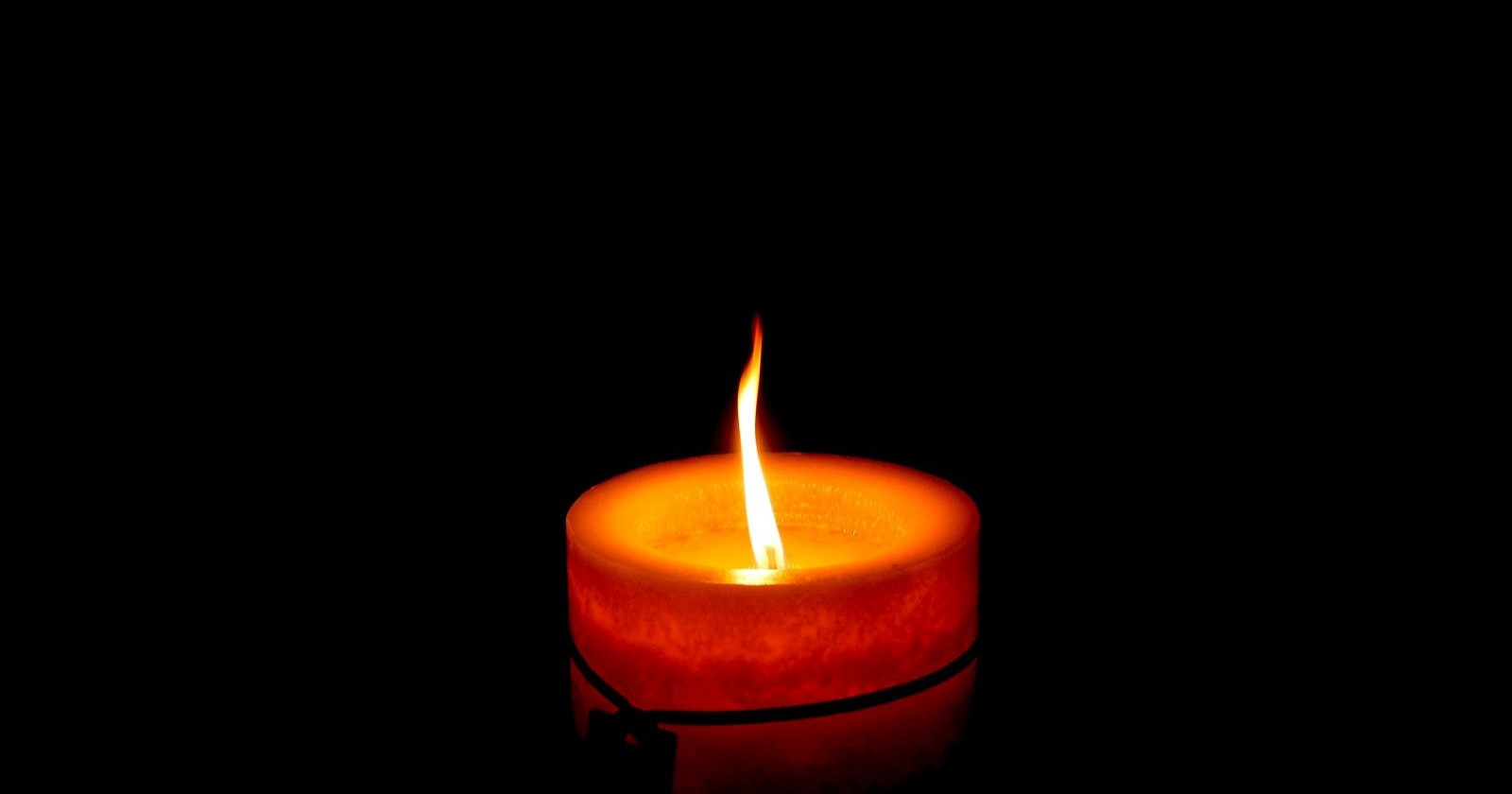 Brennende rote Kerze vor schwarzem Hintergrund als Symbolbild für den Tod der Schauspielerin Swetlana Schönfeld