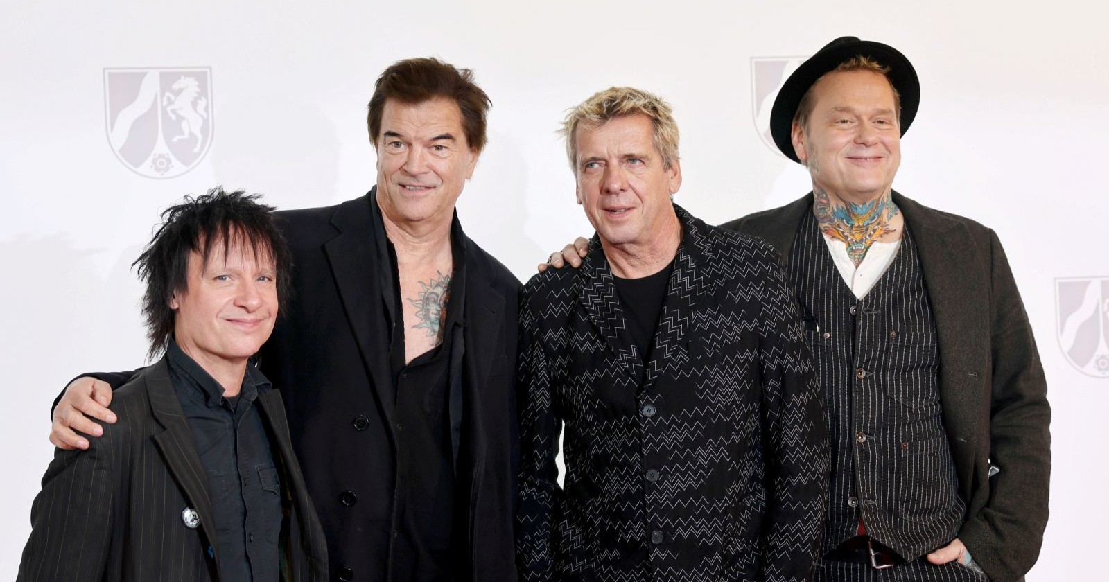 Die Toten Hosen posieren bei einem öffentlichen Auftritt vor ihrer Abschiedstour 2026 gemeinsam auf dem roten Teppich. Frontmann Campino und die Band präsentierten zuletzt ihr neues Album „Trink aus, wir müssen gehen!“.