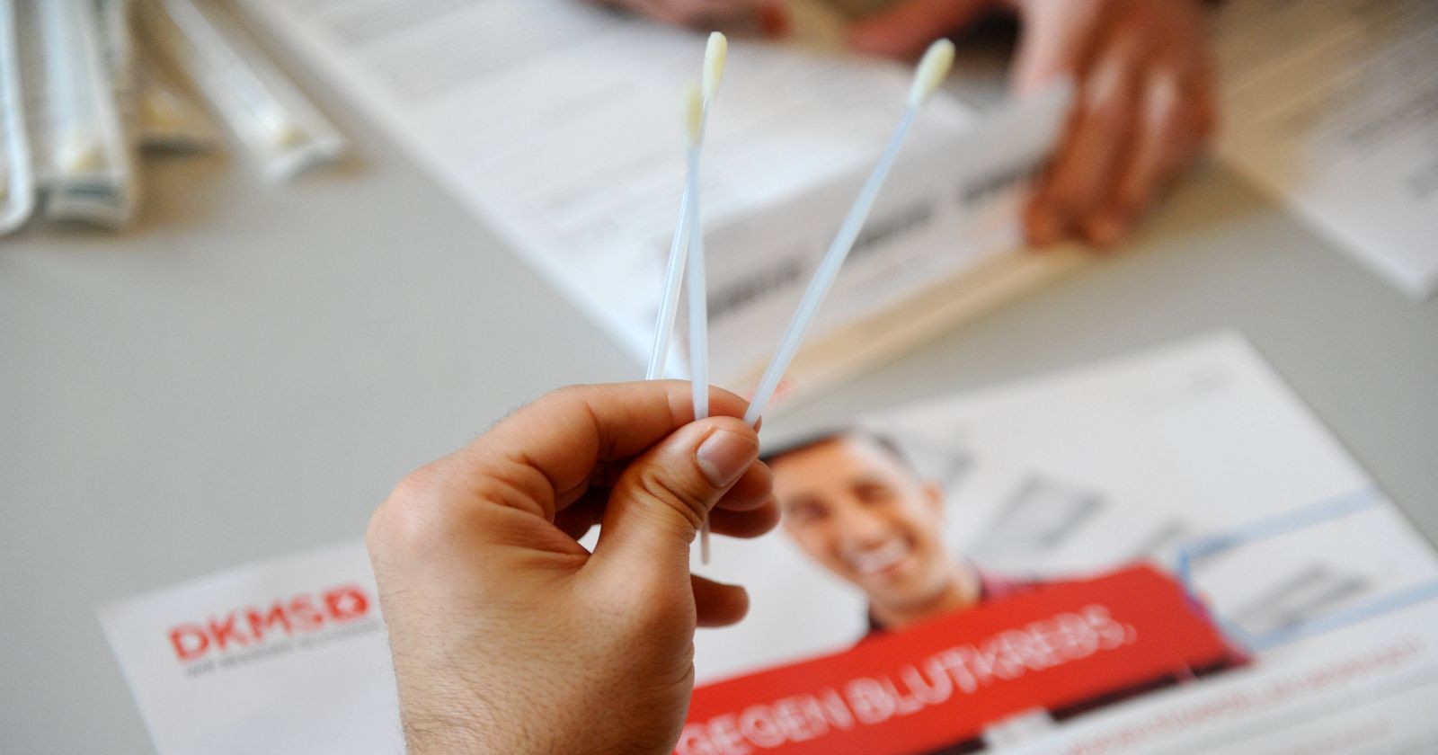 Mensch hält zwei lange Wattestäbchen in der Hand