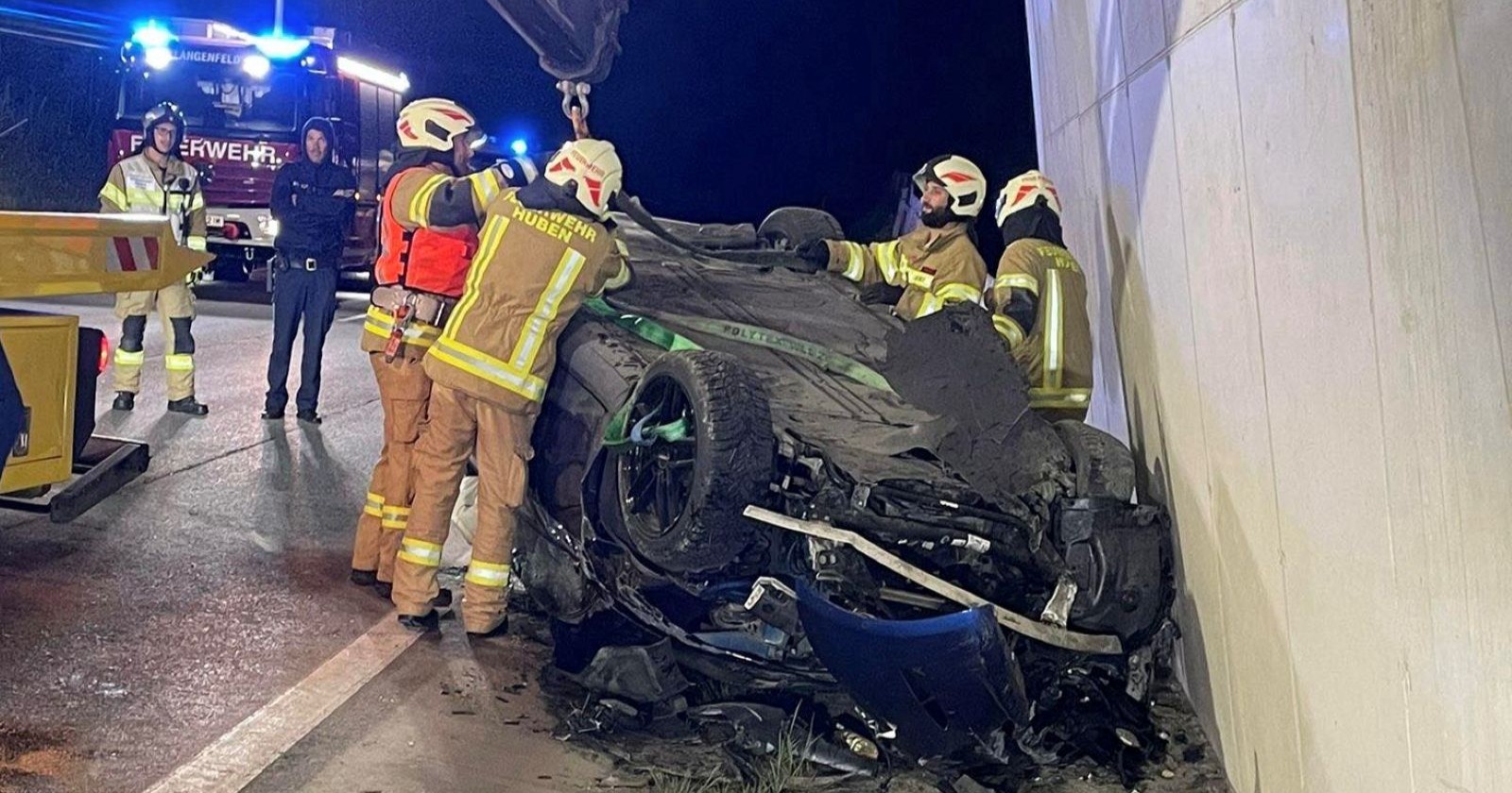 Einsatzkräfte der Feuerwehr arbeiten an einem zerstörten Auto, das nach einem Unfall in Längenfeld auf dem Dach liegt