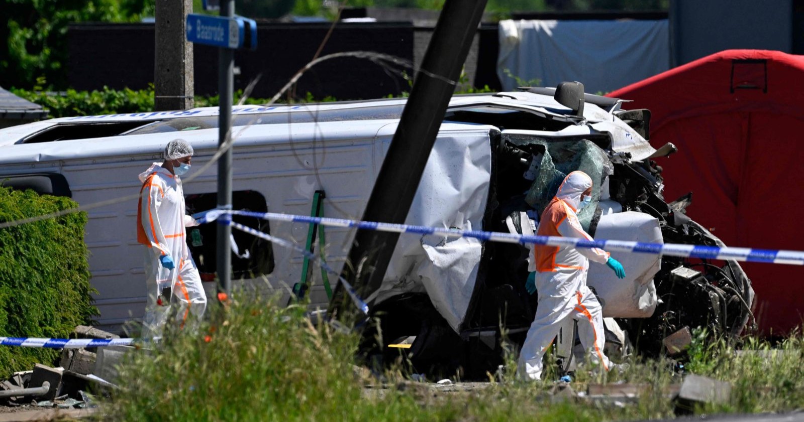 Zugunfall Belgien Schulbus: zerstörter Kleinbus nach Kollision mit Zug am Bahnübergang in Buggenhout mit Einsatzkräften vor Ort