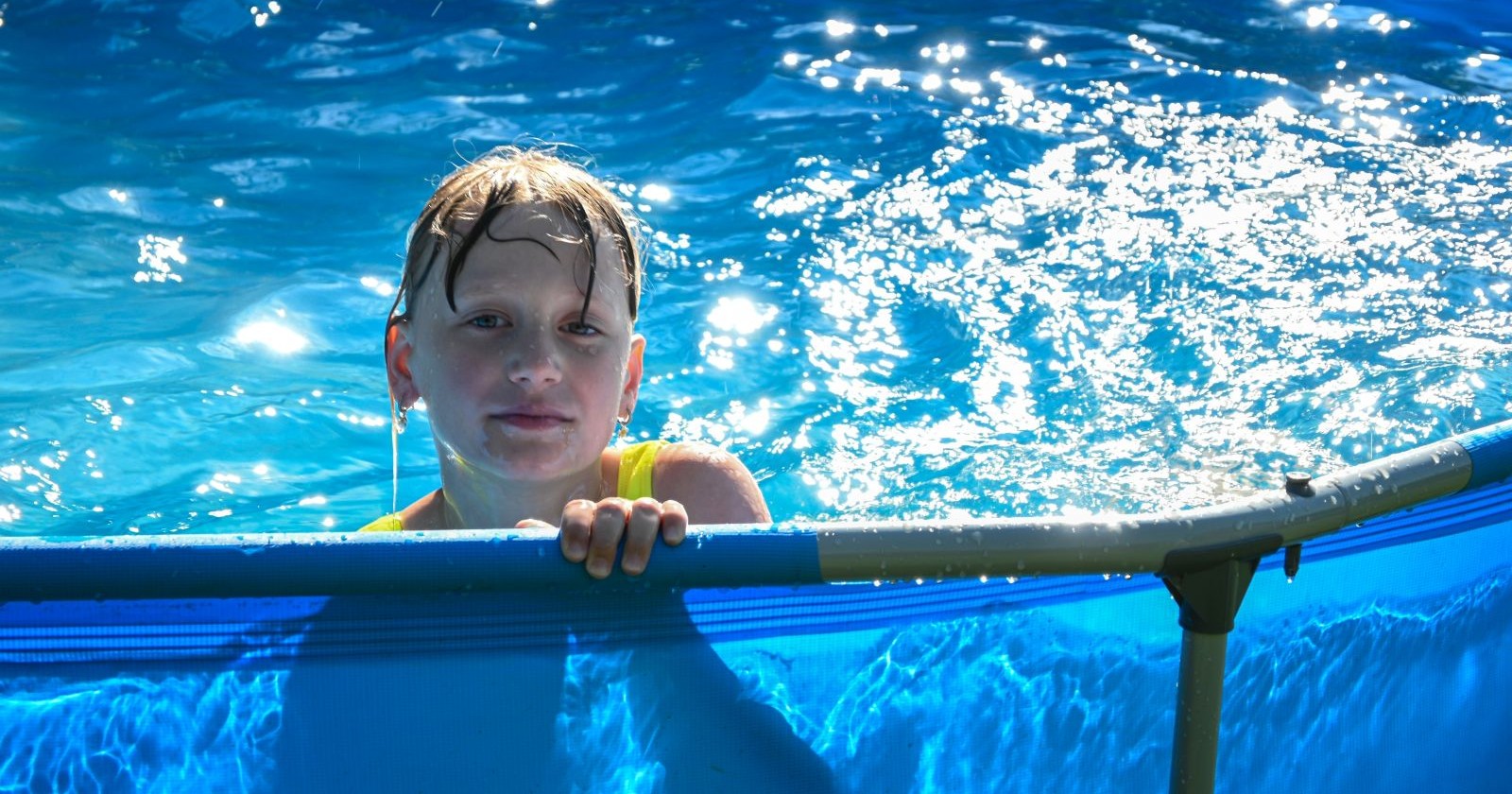 Ein Kind spielt in einem Aufstellpool bei Sonnenschein