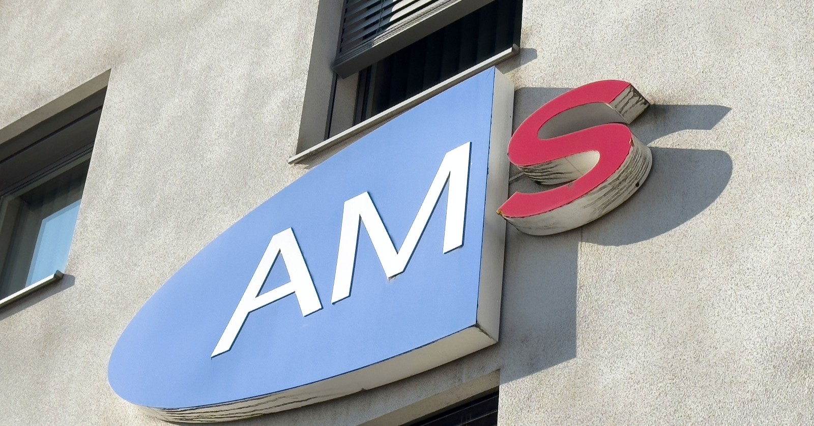 AMS-Logo vor einem Gebäude in Villach.