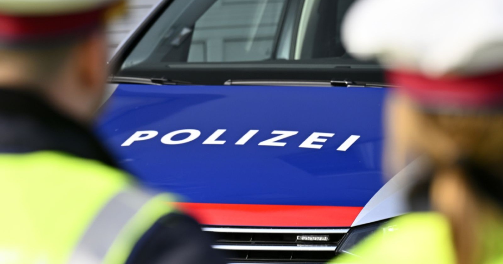 Zwei Polizisten stehen vor einem Polizeiauto