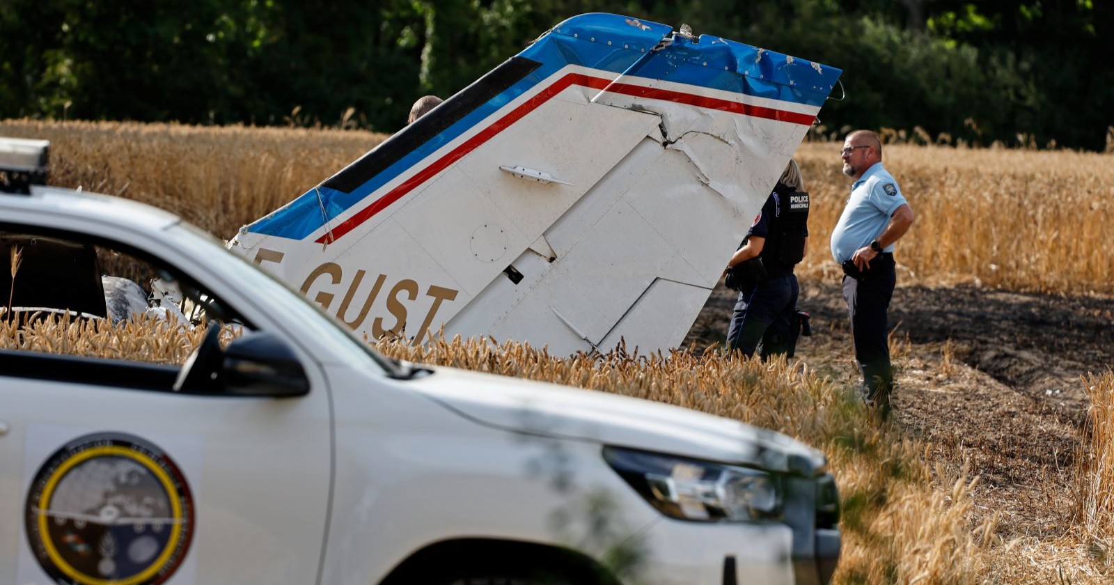 Flugzeugteile liegen am Boden, davor steht ein Polizeiauto