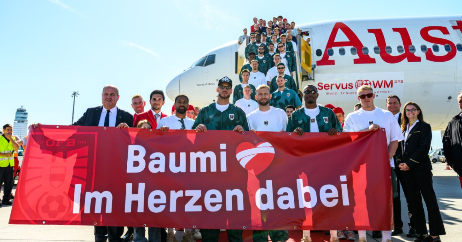 Mehrere Menschen stehen vor einem Flugzeug und halten ein Transparent hoch