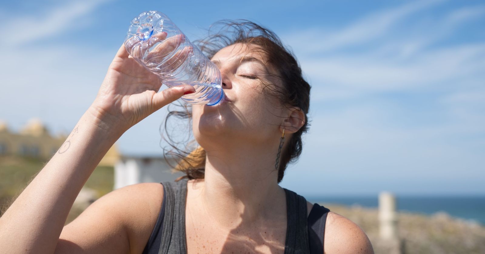 Frau trinkt Wasser während der Hitzewelle in Österreich, um sich bei extremer Hitze und Temperaturen bis zu 40 Grad abzukühlen.