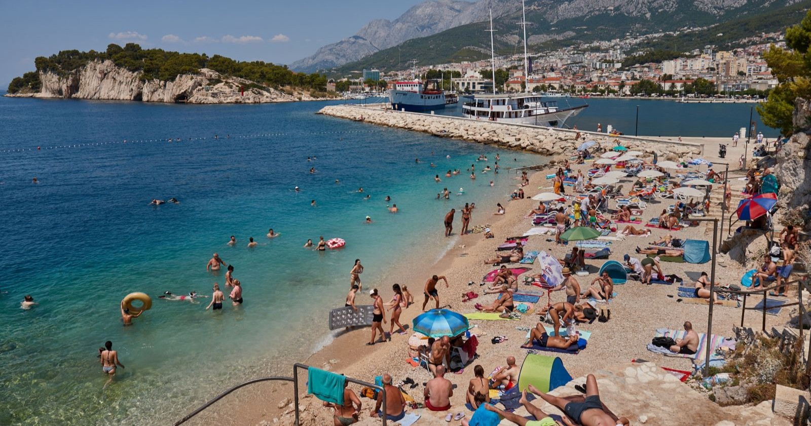 Hitzewelle Kroatien: Überfüllter Strand an der Adria bei hohen Temperaturen und Badenden im Meer