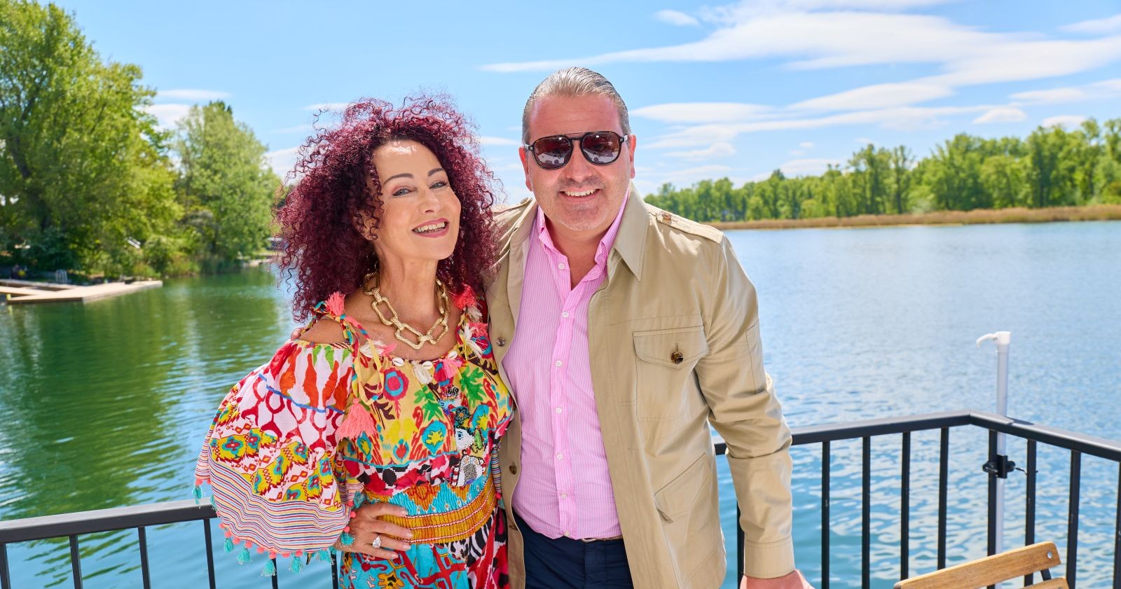 Christina Mausi Lugner und Schwiegersohn Leo Lugner lächeln gemeinsam auf einer Terrasse am Wasser im Wiener Strandcafé