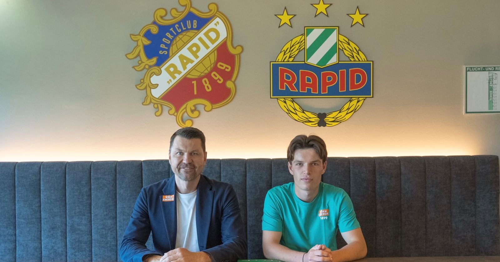 Fußballprofi Nicolas Bajlicz im Shirt des SK Rapid Wien lächelt bei der Vertragsunterzeichnung in der Geschäftsstelle