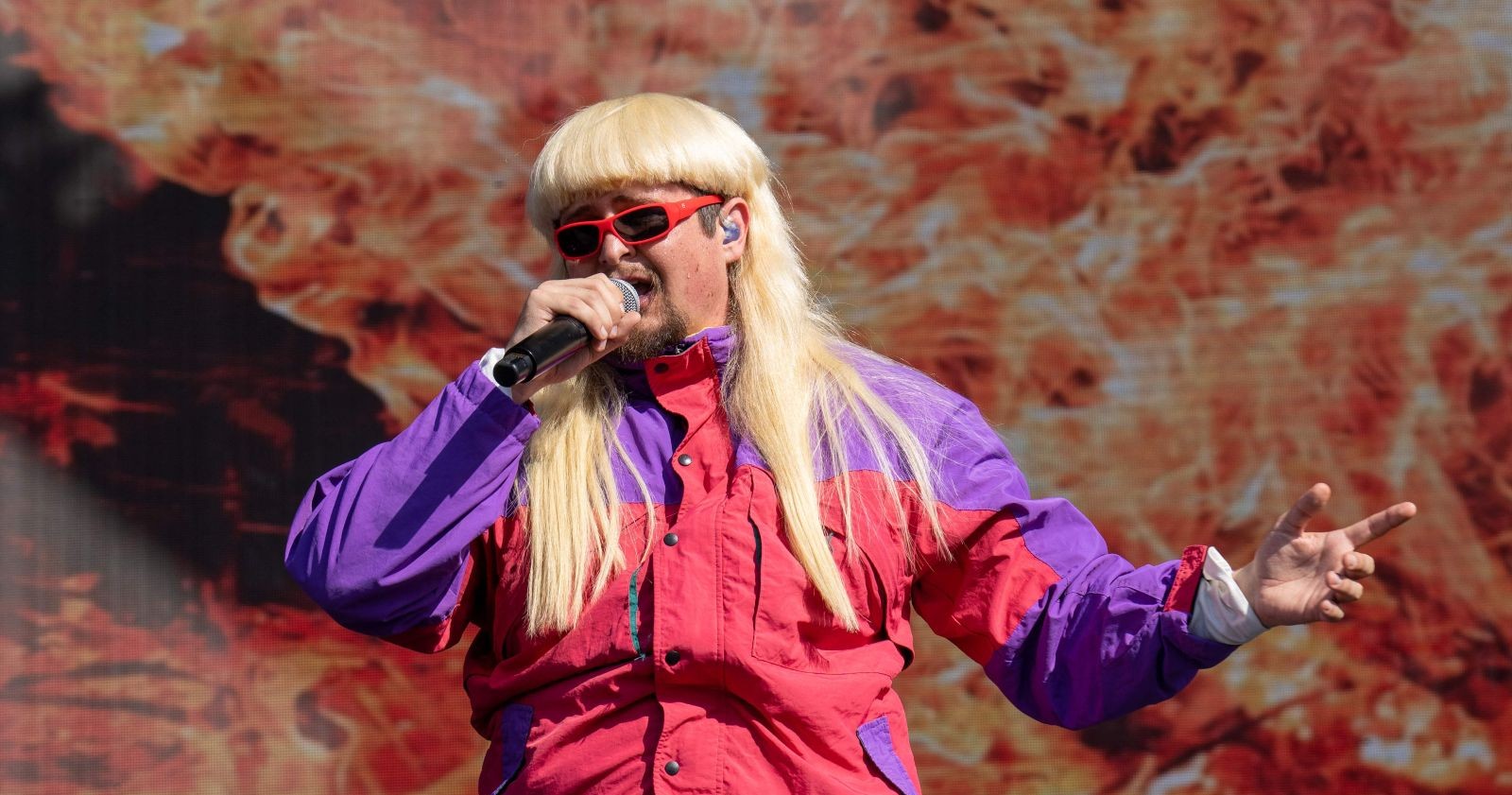 Oliver Tree singt auf der Bühne mit Mikrofon und auffälligem Outfit während eines Konzerts