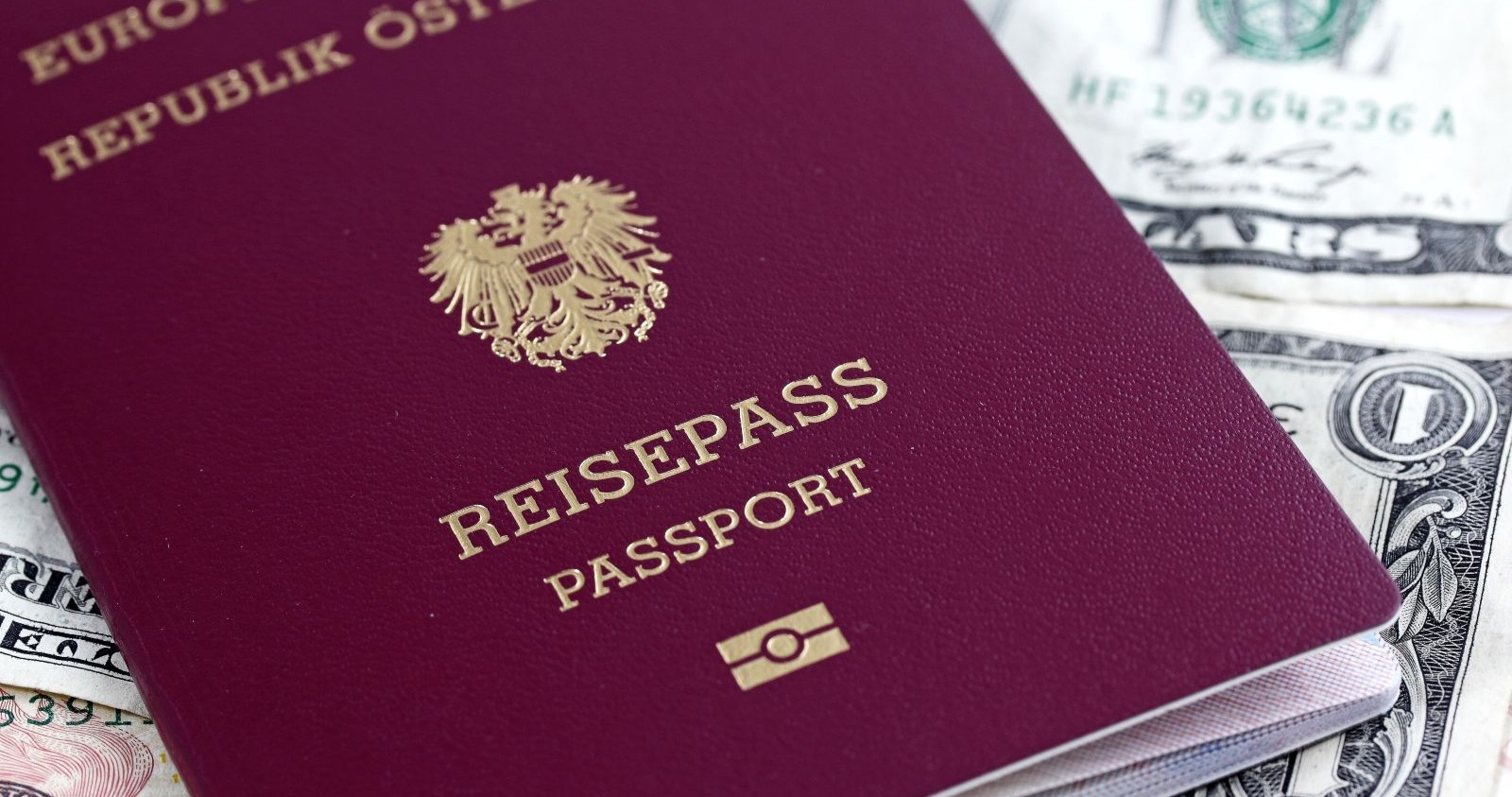 Österreichischer Reisepass im neuen Design mit Adler-Wappen auf Geldscheinen als Hintergrund, Symbol für Sicherheit und internationale Reisefreiheit